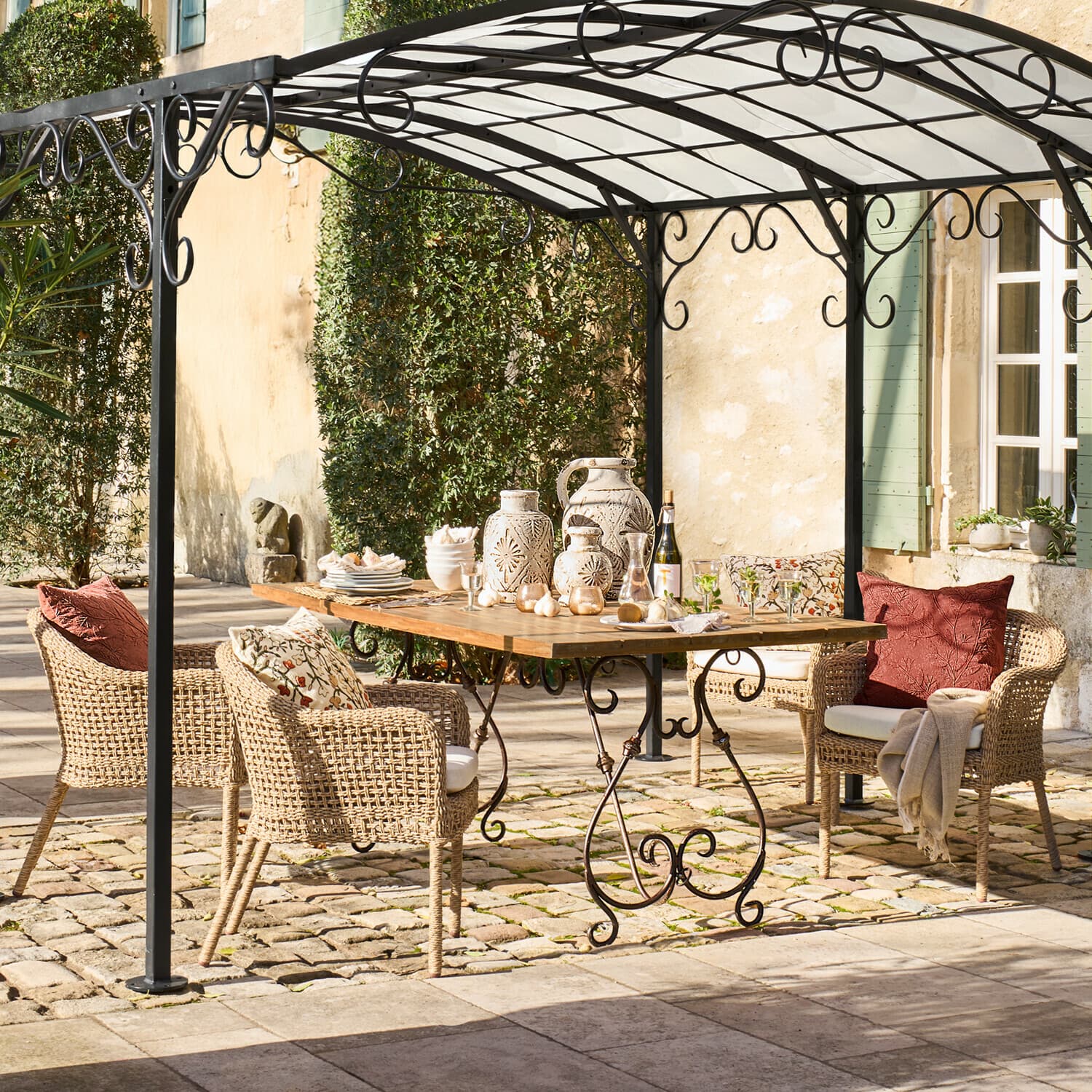 Gartenmöbel-Set aus Rattan und Holz unter einem Metallpavillon auf Steinboden