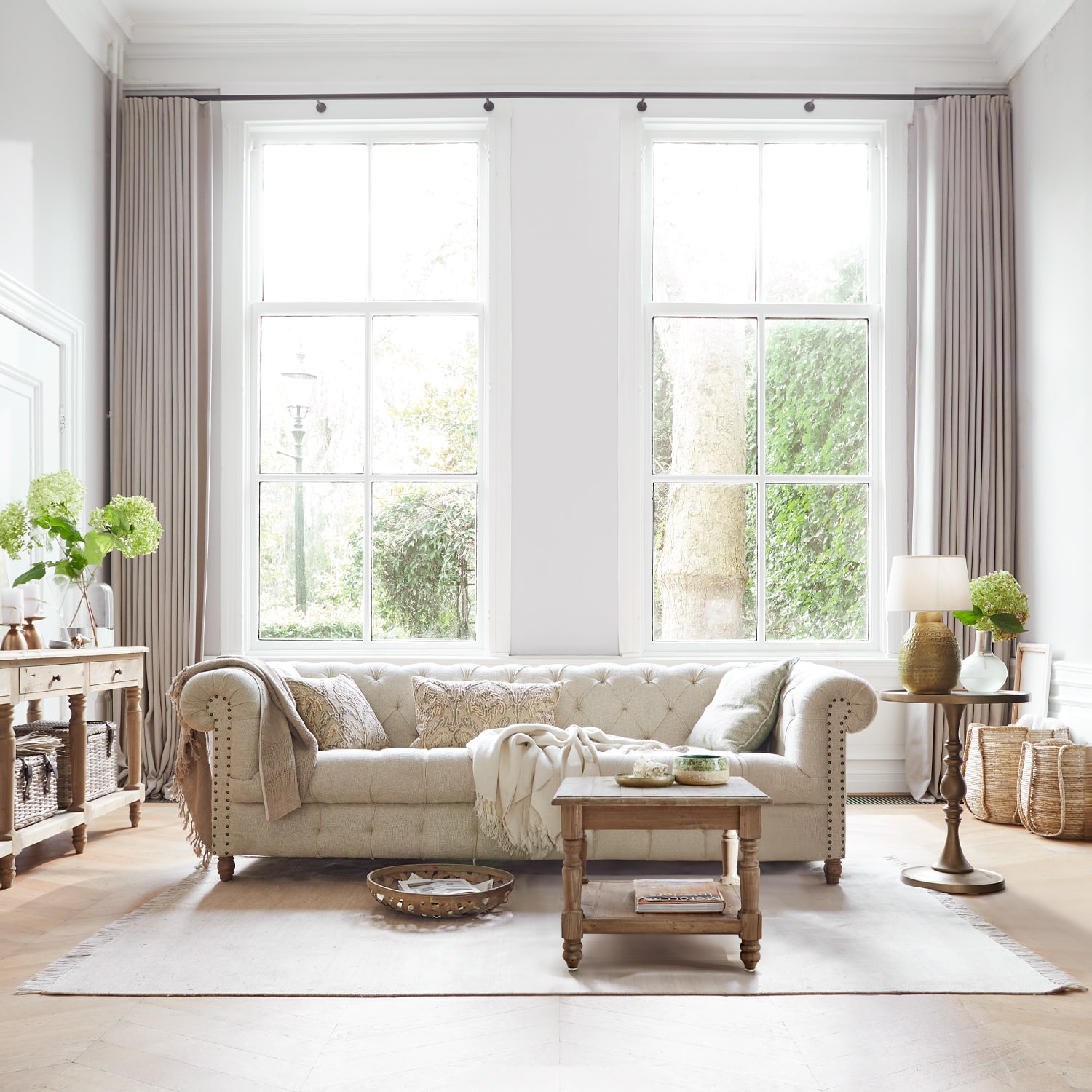 Beige gepolstertes Sofa aus Stoff in hellem Wohnzimmer mit Holztisch und Dekorationen
