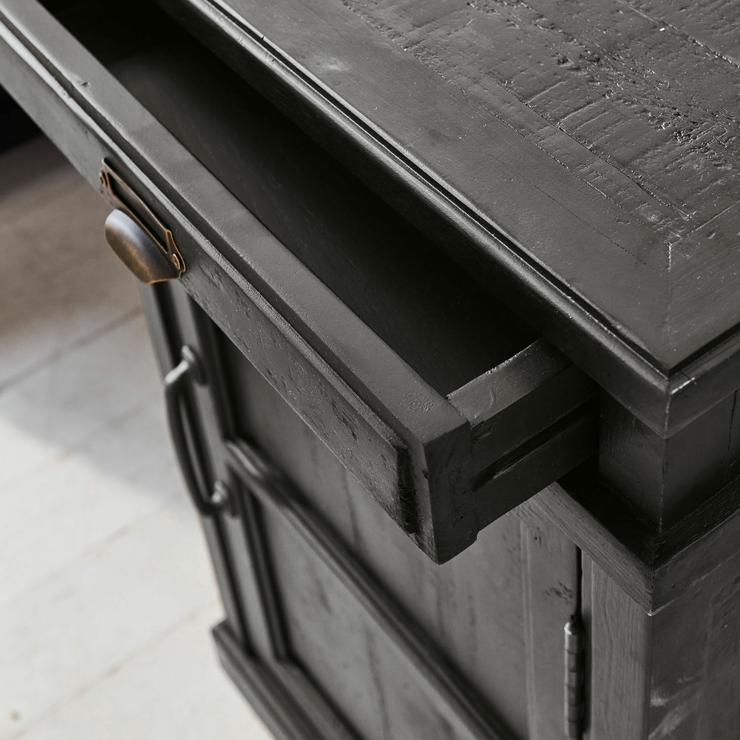 Schwarzer Holzschrank mit geöffneter Schublade und Metallgriff zur Aufbewahrung im Wohnzimmer