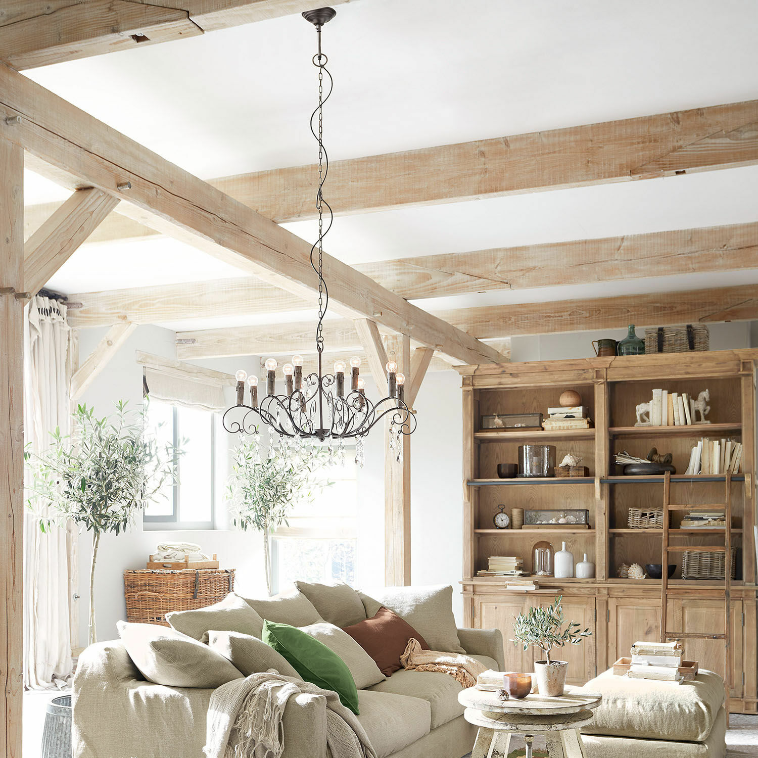 Gemütliches Wohnzimmer mit beigem Sofa, Holzschrank und rustikalem Metall-Kronleuchter