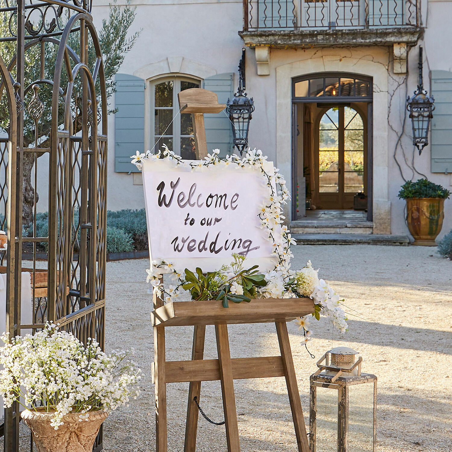 Holzs easel mit Willkommensschild zur Hochzeit, verziert mit weißen Blumen in rustikalem Ambiente