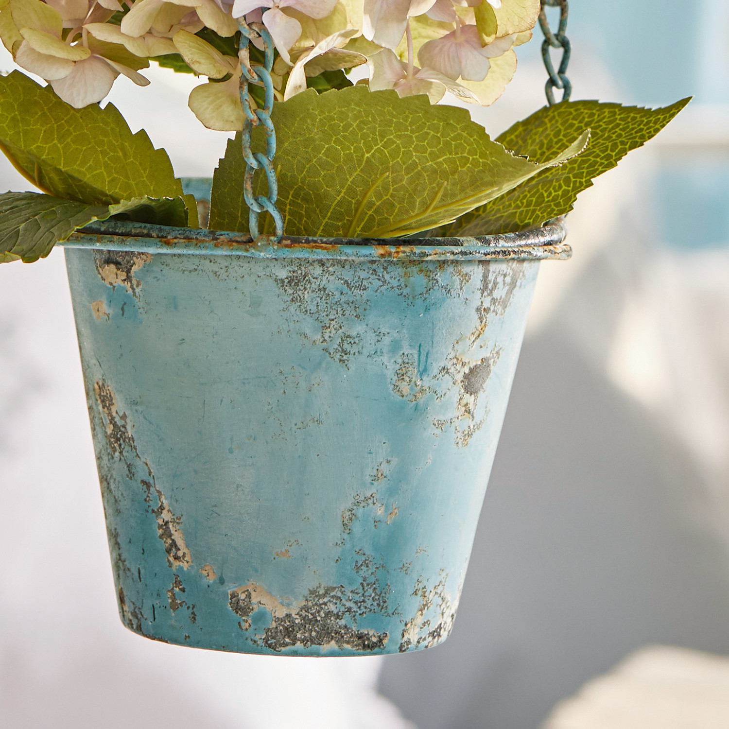 Hängender blauer Metalltopf mit Used-Look und grünen Dekoblättern für Garten oder Balkon