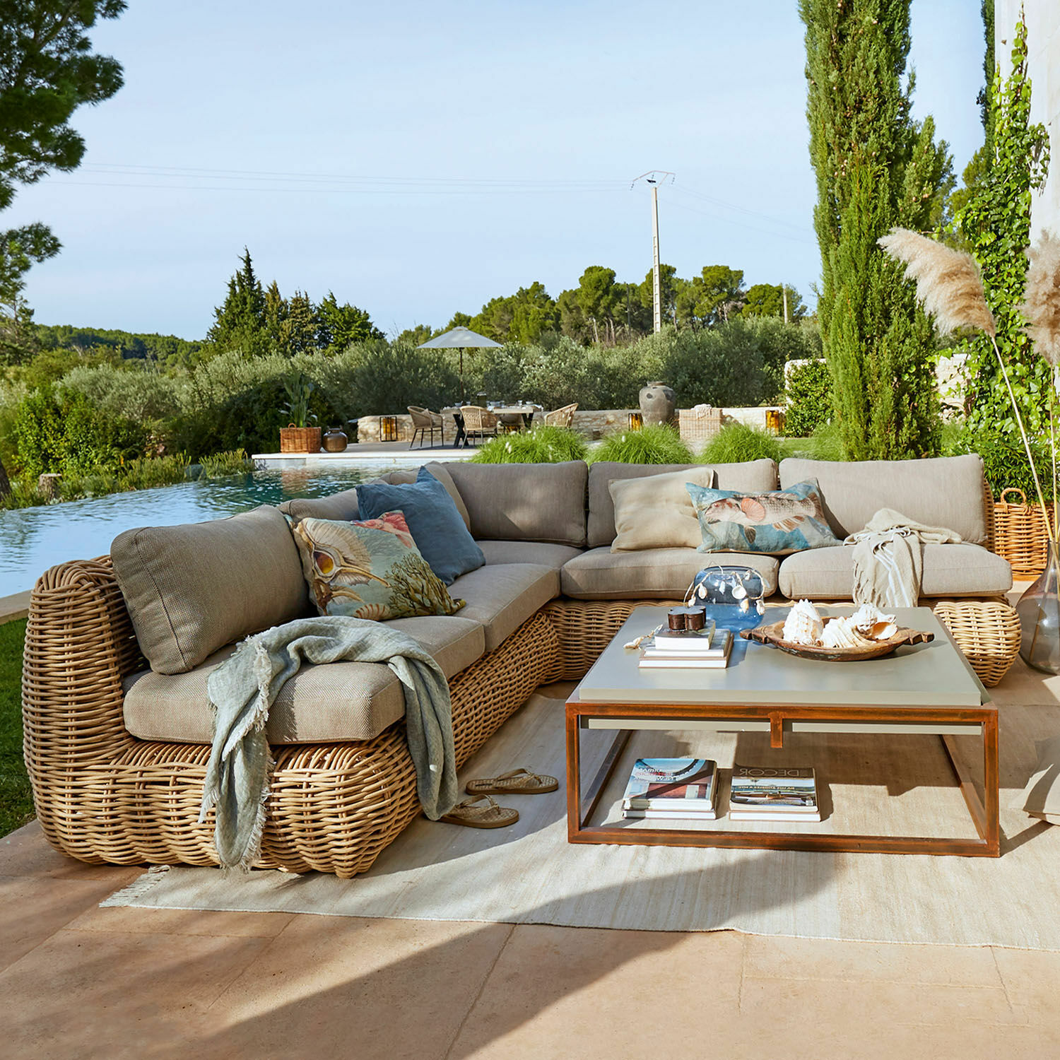 Ecksofa aus Rattan in Beige mit Kissen und Couchtisch auf Terrasse am Pool