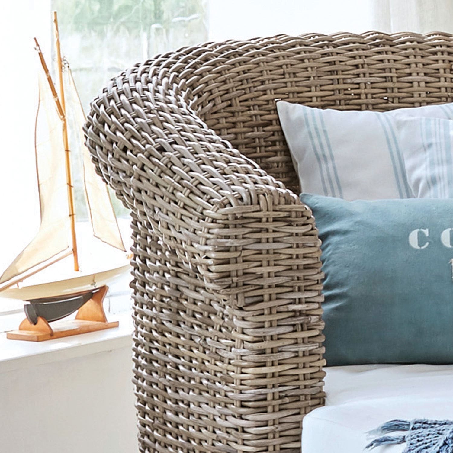 Sofa aus geflochtenem Rattan in Naturfarbe mit blauen und weißen Kissen für gemütliches Wohnen