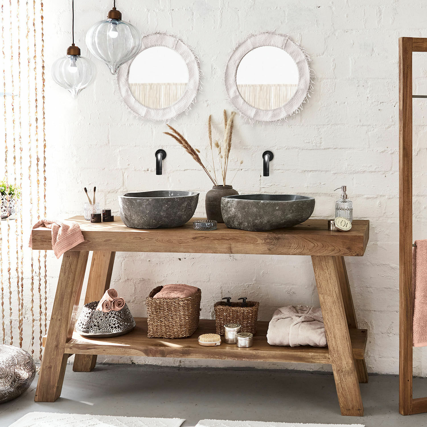 Holz-Badezimmerkonsole mit zwei schwarzen Steinwaschbecken und runden Spiegeln an weißer Wand