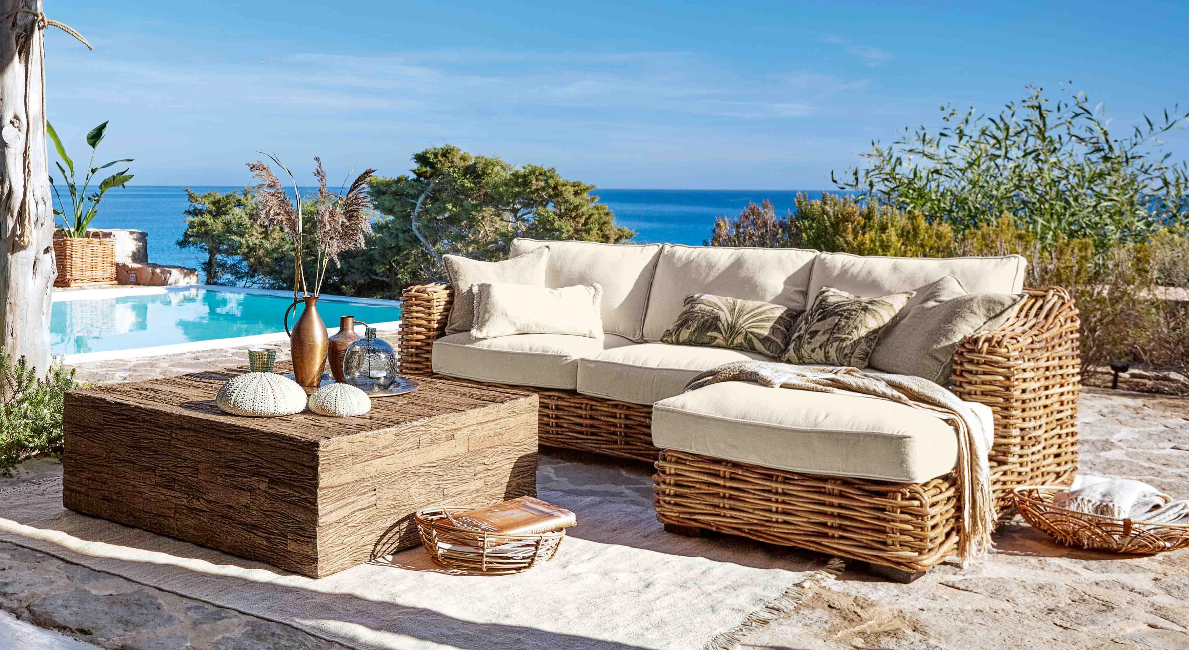 Rattan-Gartenmöbel mit cremefarbenen Polstern am Pool mit Meerblick für Outdoor-Lounge