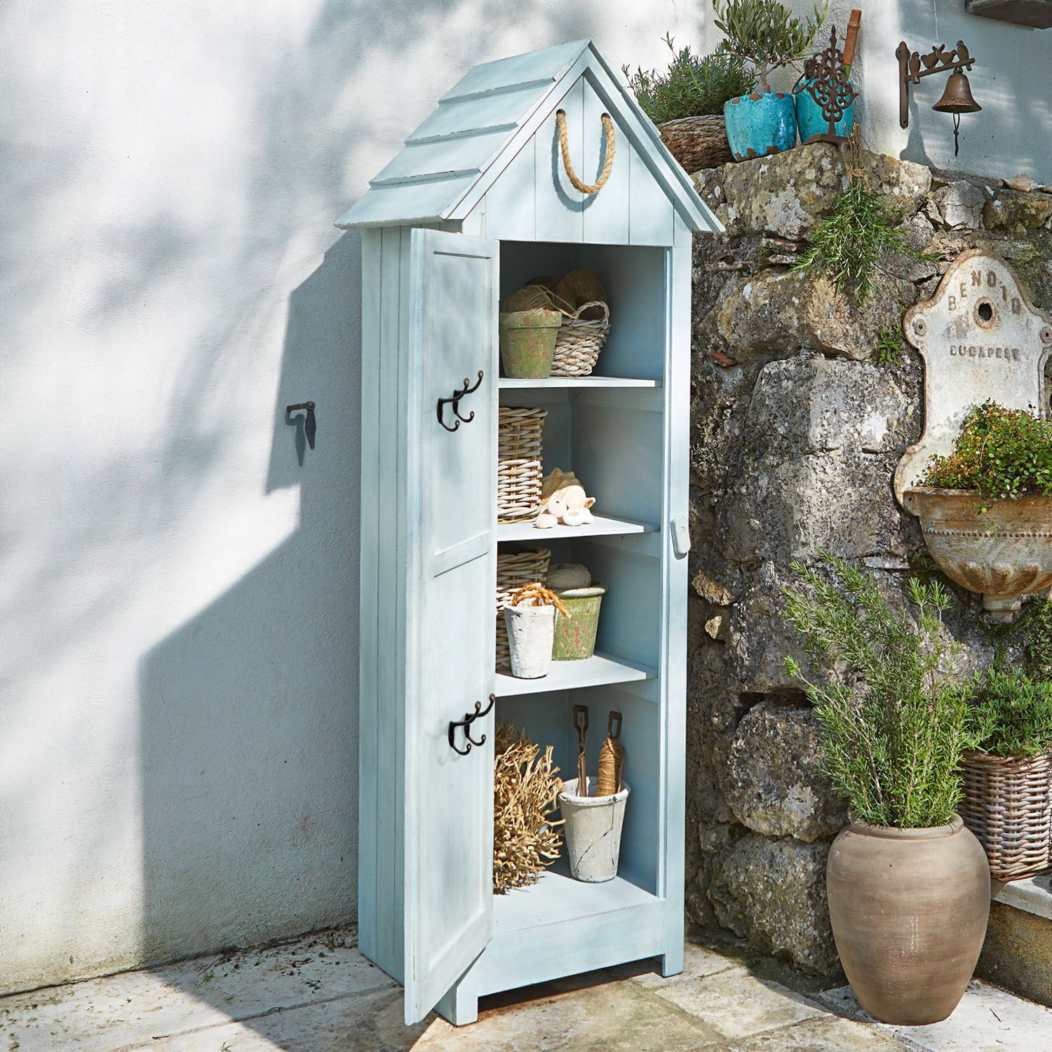 Hellblauer Holz-Gartenschrank mit Dach und Regalen, Dekorationen und Pflanzen daneben