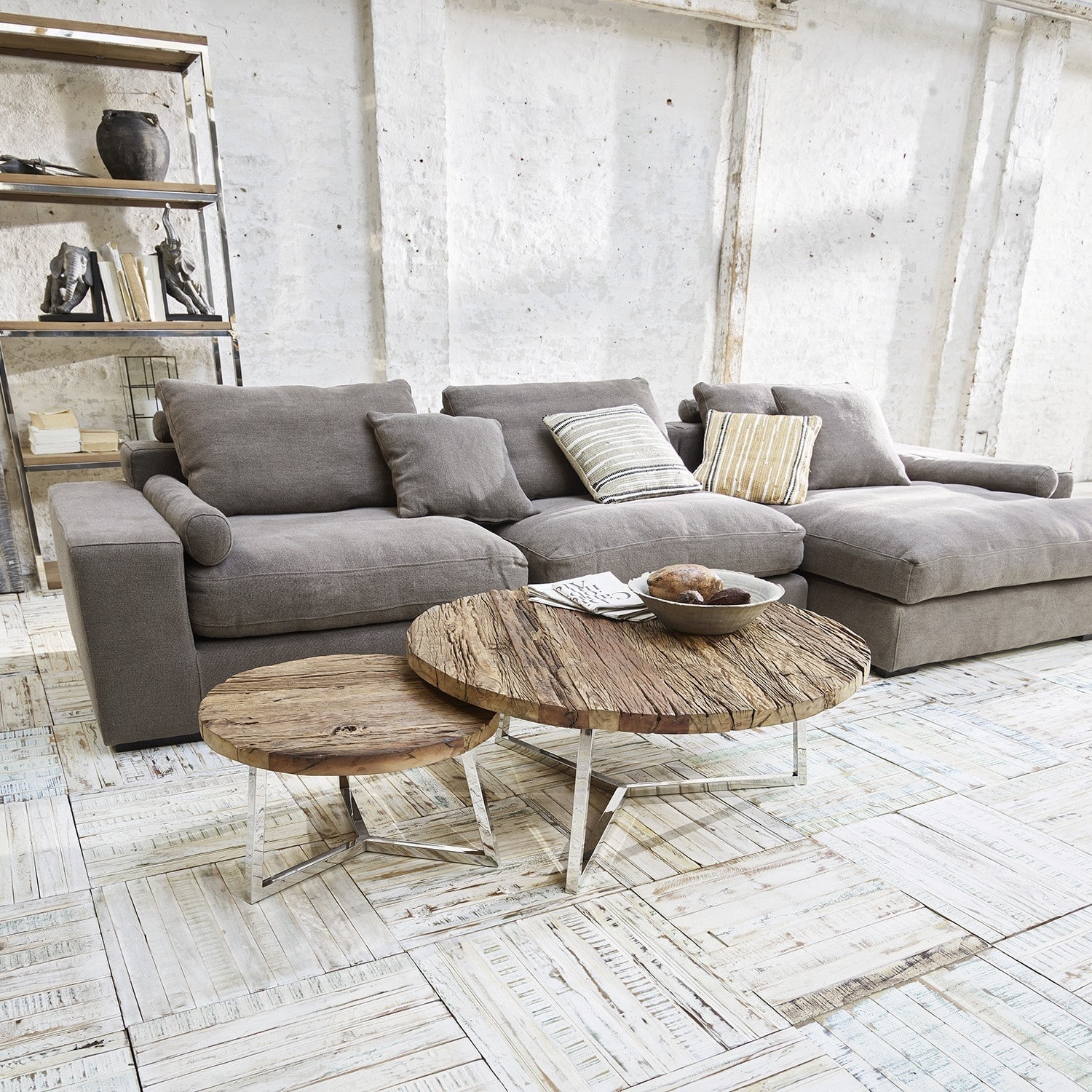 Graues Stoffsofa mit Kissen und zwei runden Couchtischen aus Holz auf Metallbeinen