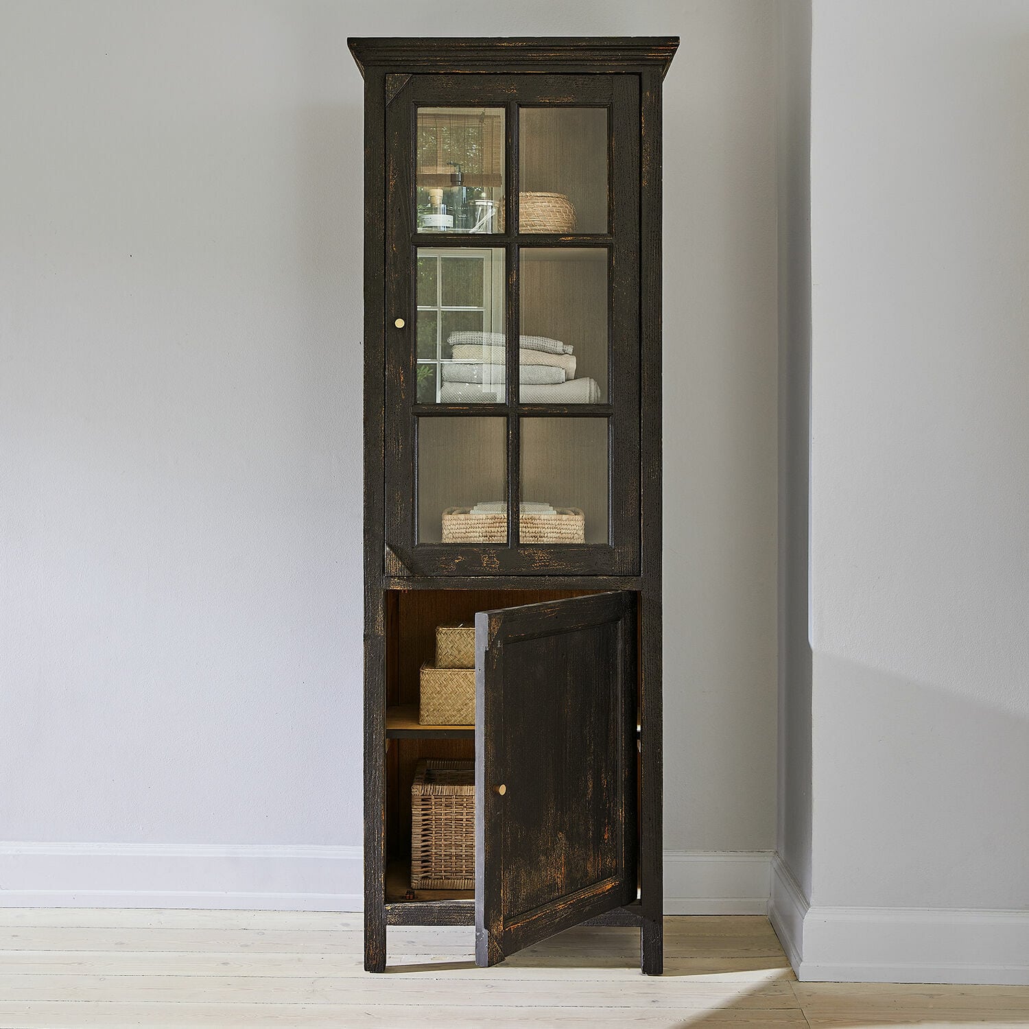 Hoher schwarzer Holzschrank mit Glastür und Regalen für Handtücher und Körbe