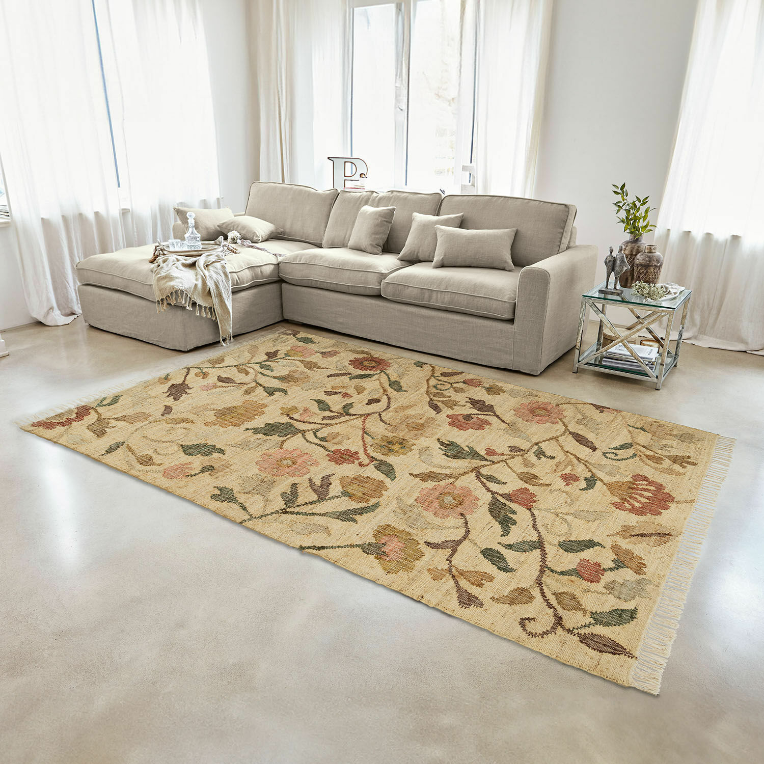 Teppich Théranelle Beiger Wollteppich mit floralem Muster im Wohnzimmer mit grauem Sofa und Glastisch