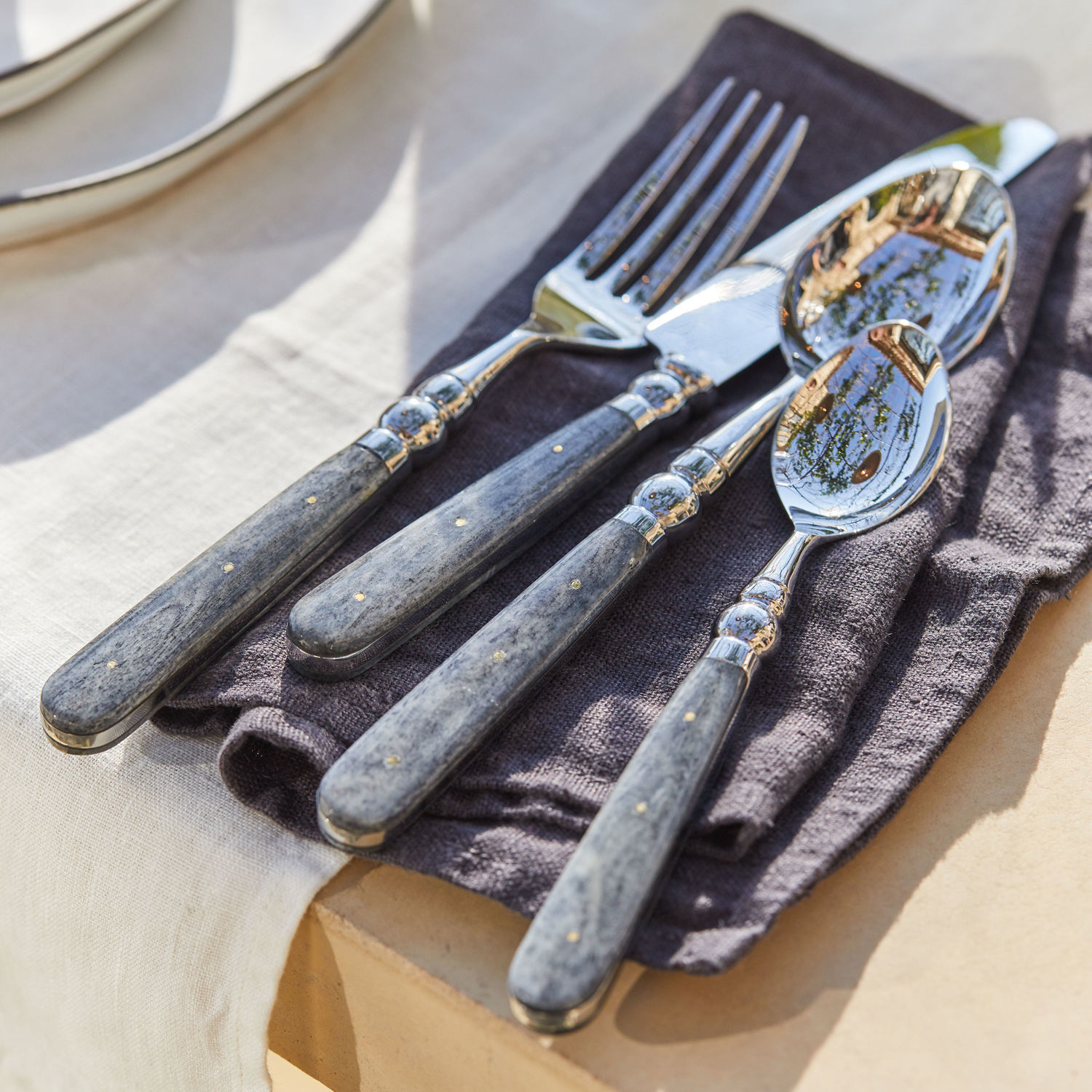 Besteck Bigeste Besteckset mit grauen Marmorgriffen und Metallenden auf dunklem Stoffserviette