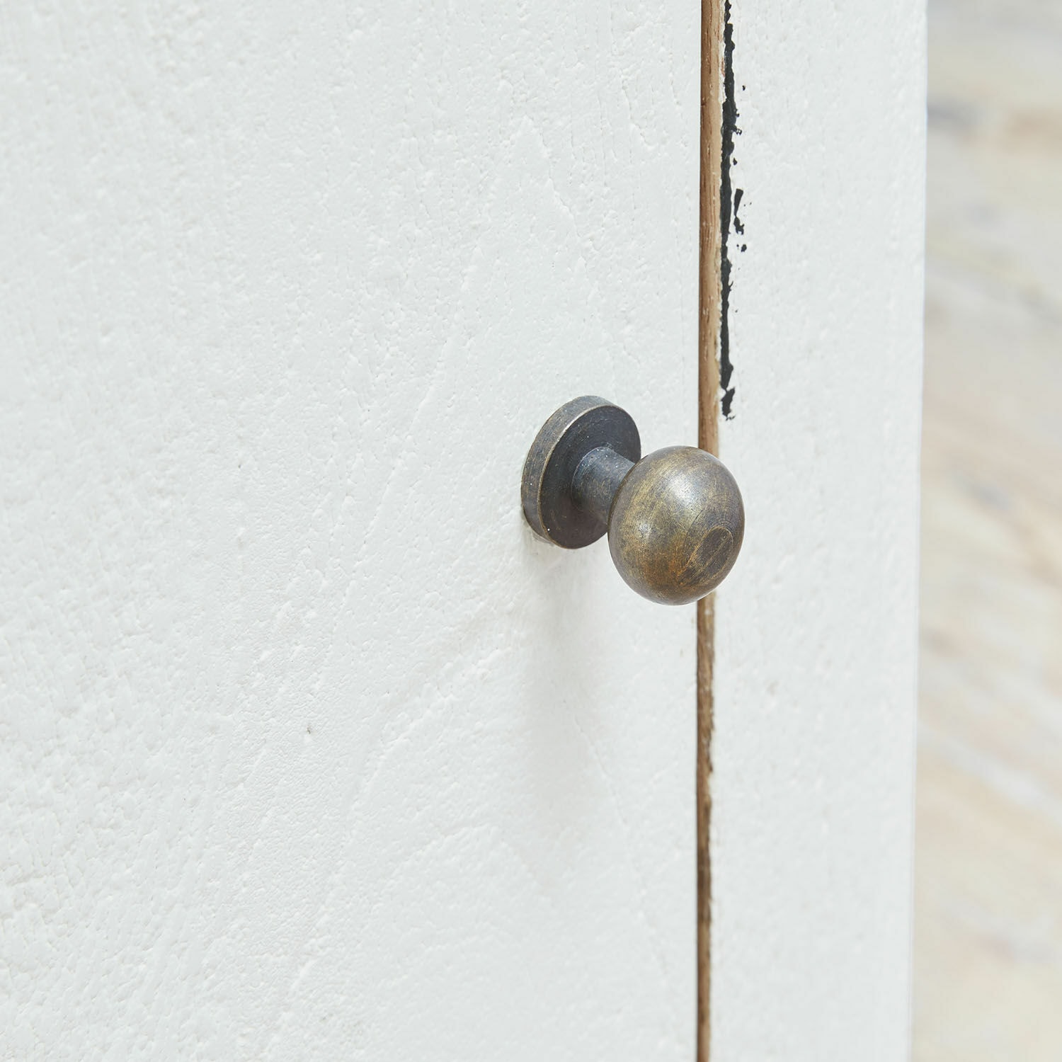 Metallrunder Möbelknauf in antikem Messing an weißer Holztür für Schrank oder Kommode