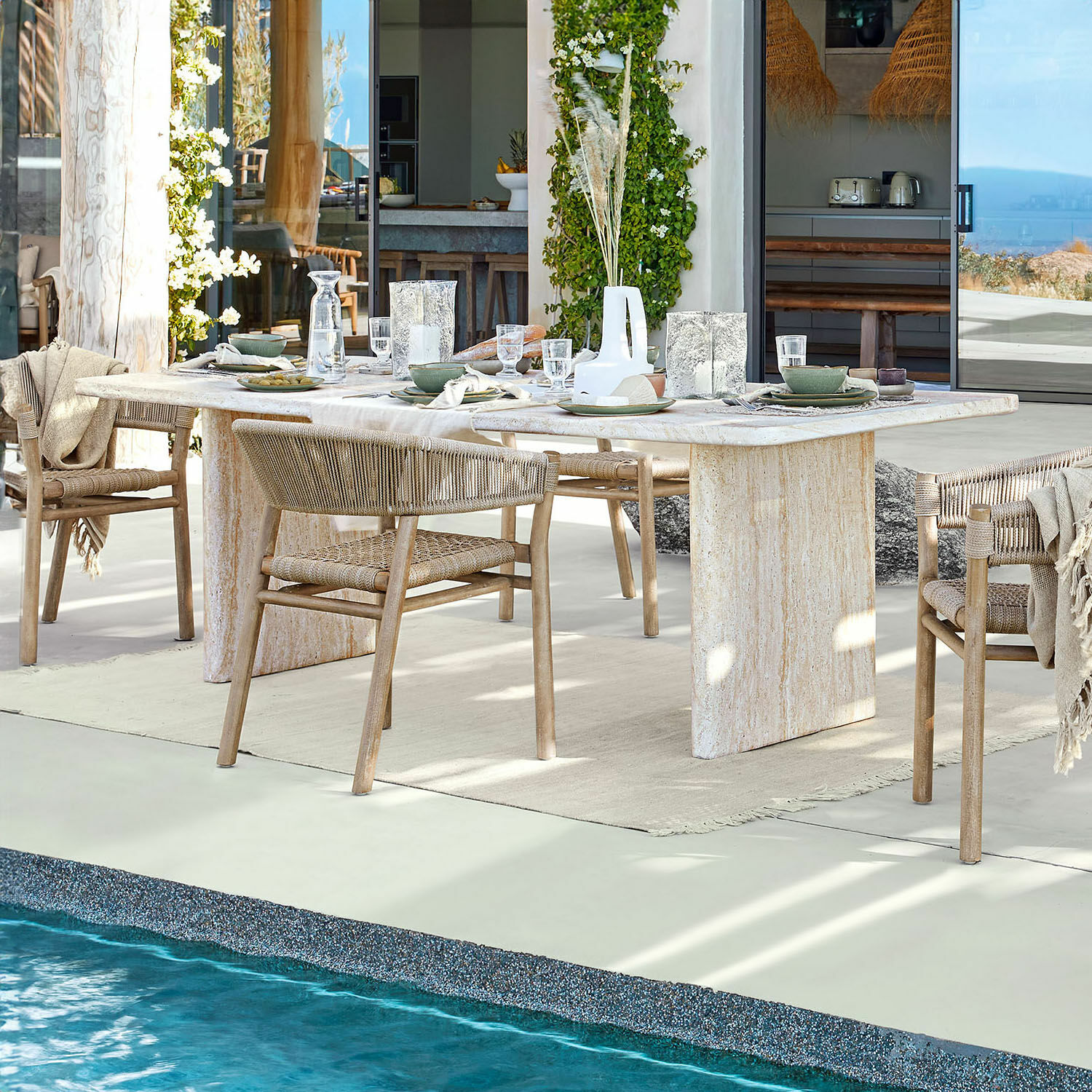 Esstisch Yveline Esstisch aus hellem Stein mit Holzstühlen und geflochtenen Rückenlehnen am Pool in modernem Haus