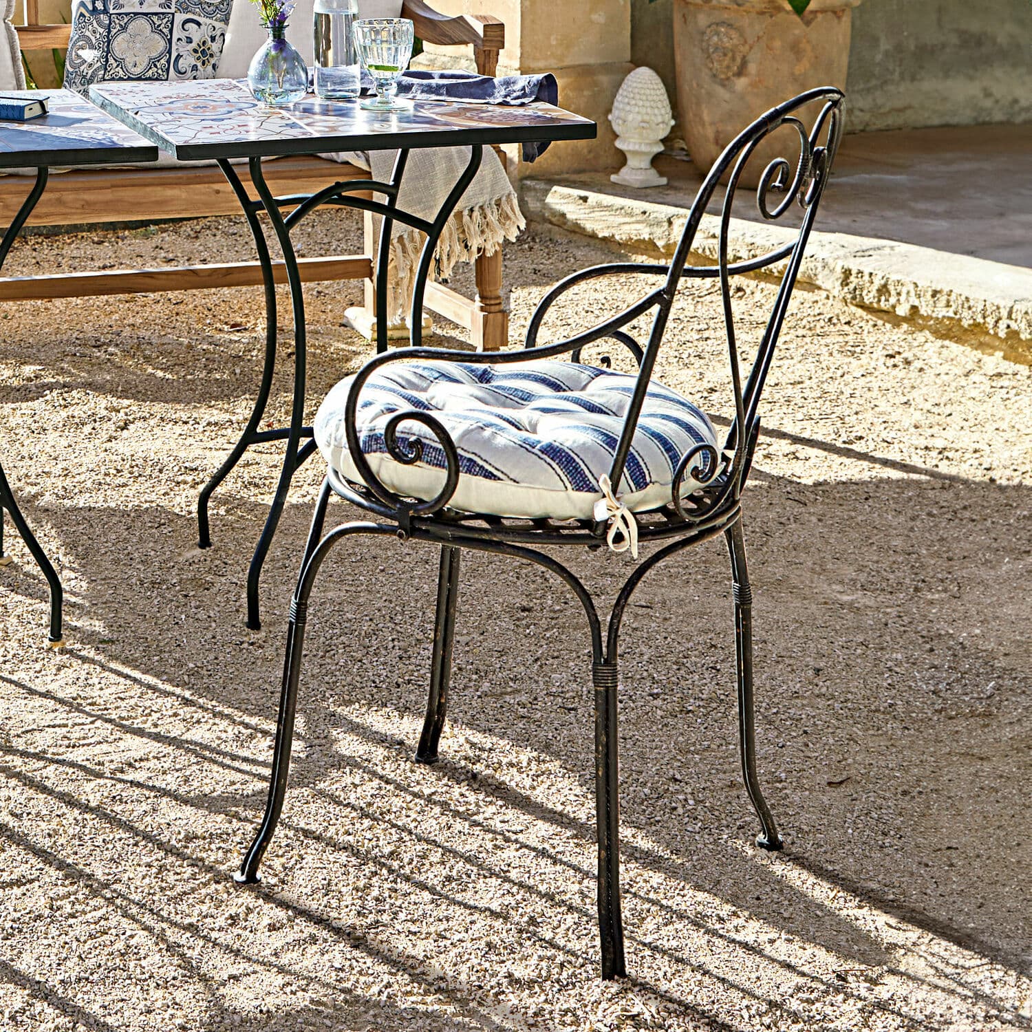 Stuhl Aube Metall-Gartenstuhl mit blau-weiß gestreiftem Polster auf sonniger Terrasse aus Kies