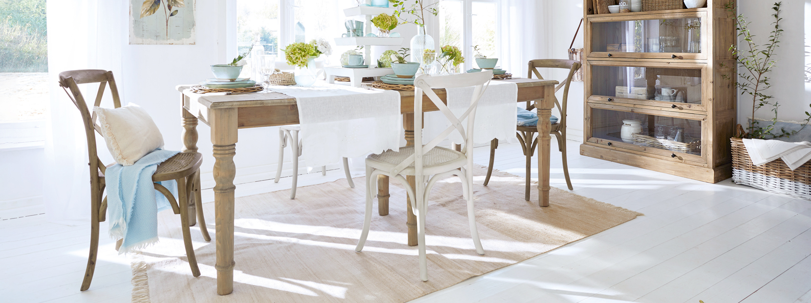 Helle Landhaus-Esszimmer mit Holztisch, gemischten Stühlen und natürlichen Dekorationen in Weiß und Beige