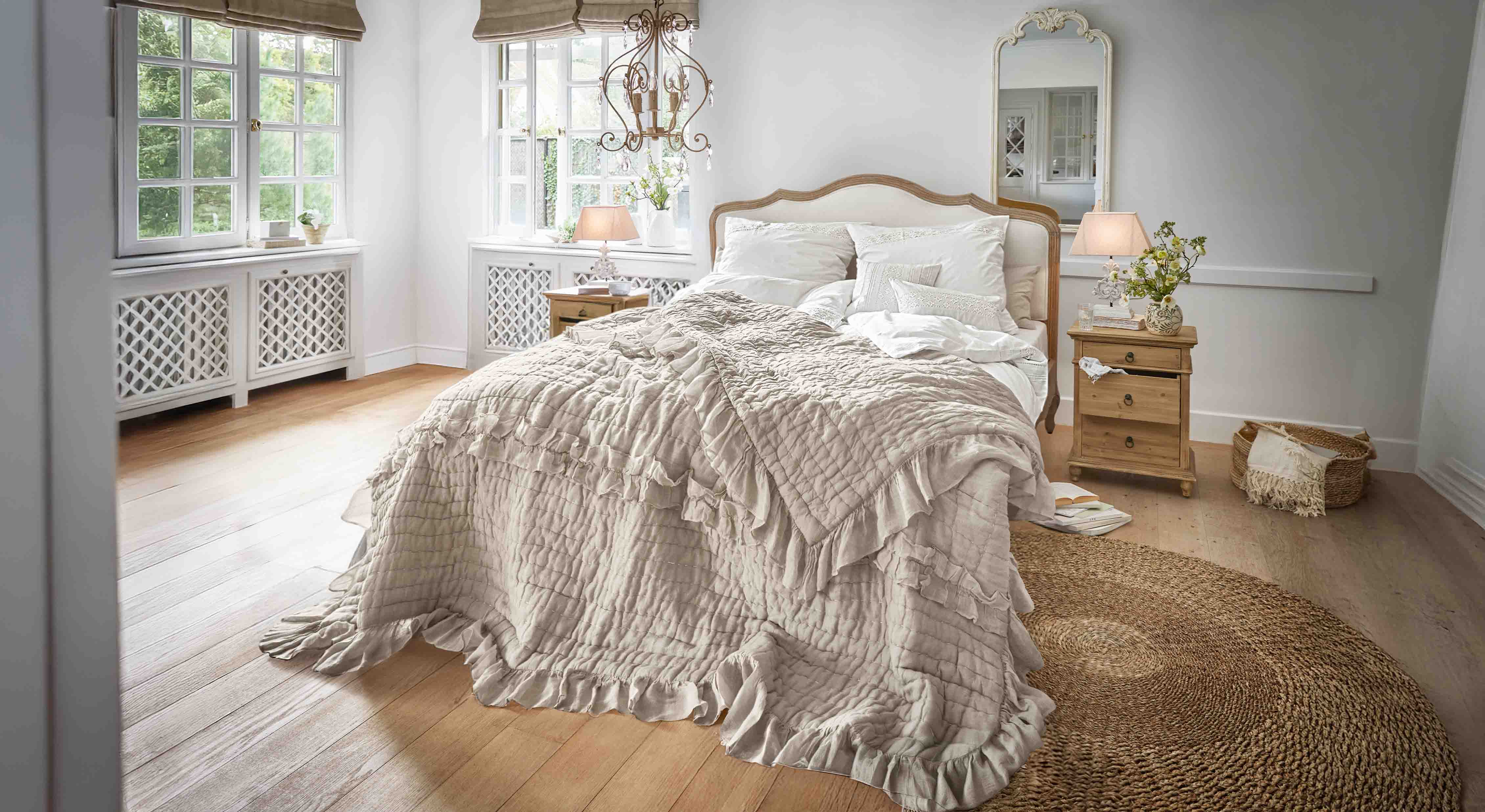 Gemütliches Schlafzimmer mit Bett in beiger Rüschendecke und Holzmöbeln im Landhausstil