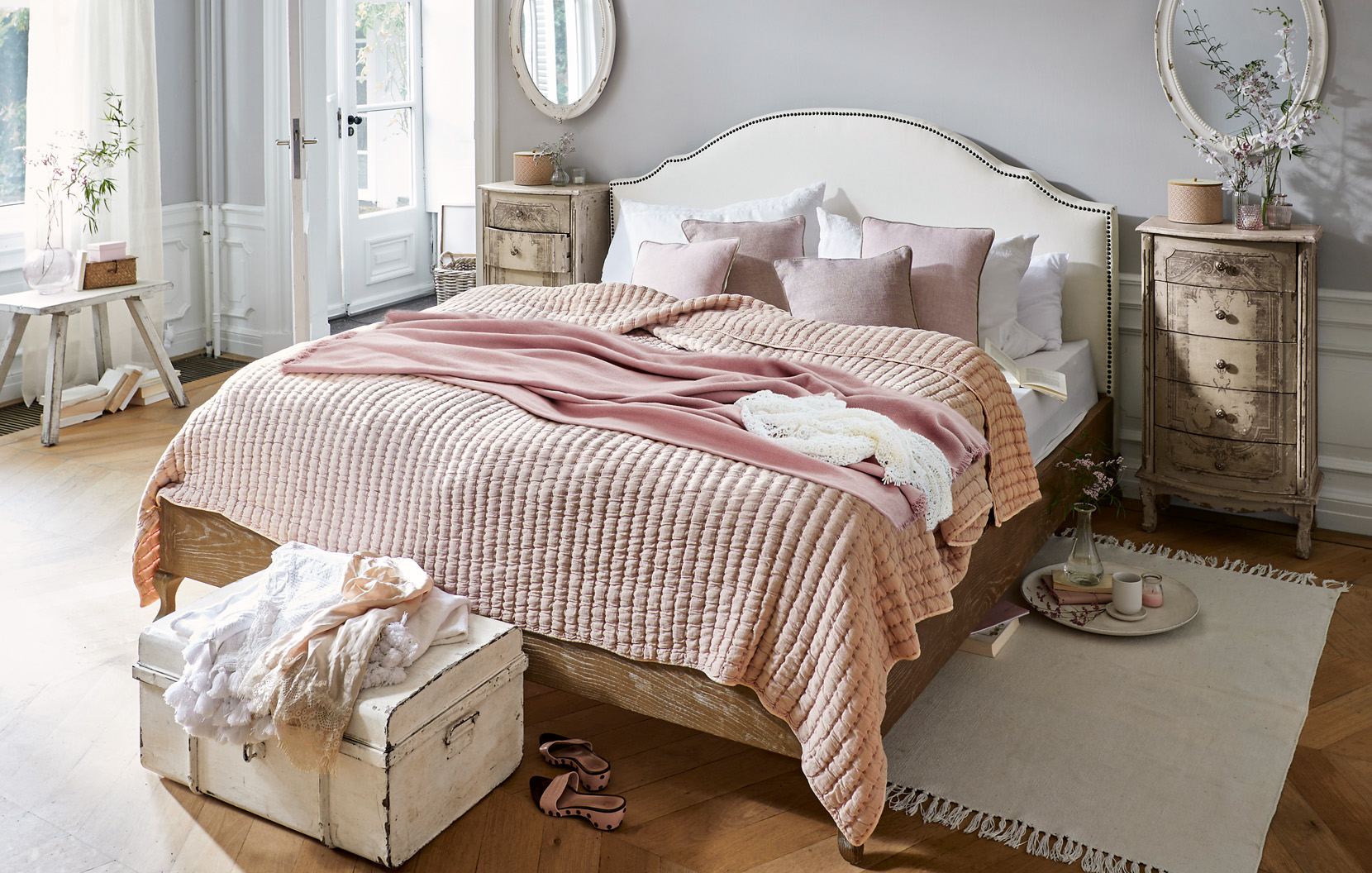 Gemütliches Shabby-Chic-Schlafzimmer mit rosa Bettdecke und vintage Holzmöbeln im Landhausstil
