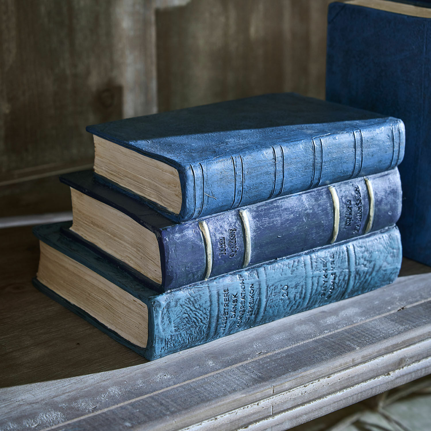 Drei dekorative blaue Bücher im Vintage-Stil auf einem Holzregal als Wohnaccessoire