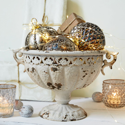 Dekorative Schale aus antik wirkendem Metall im Vintage-Stil mit Christbaumkugeln und LED-Lichterkette