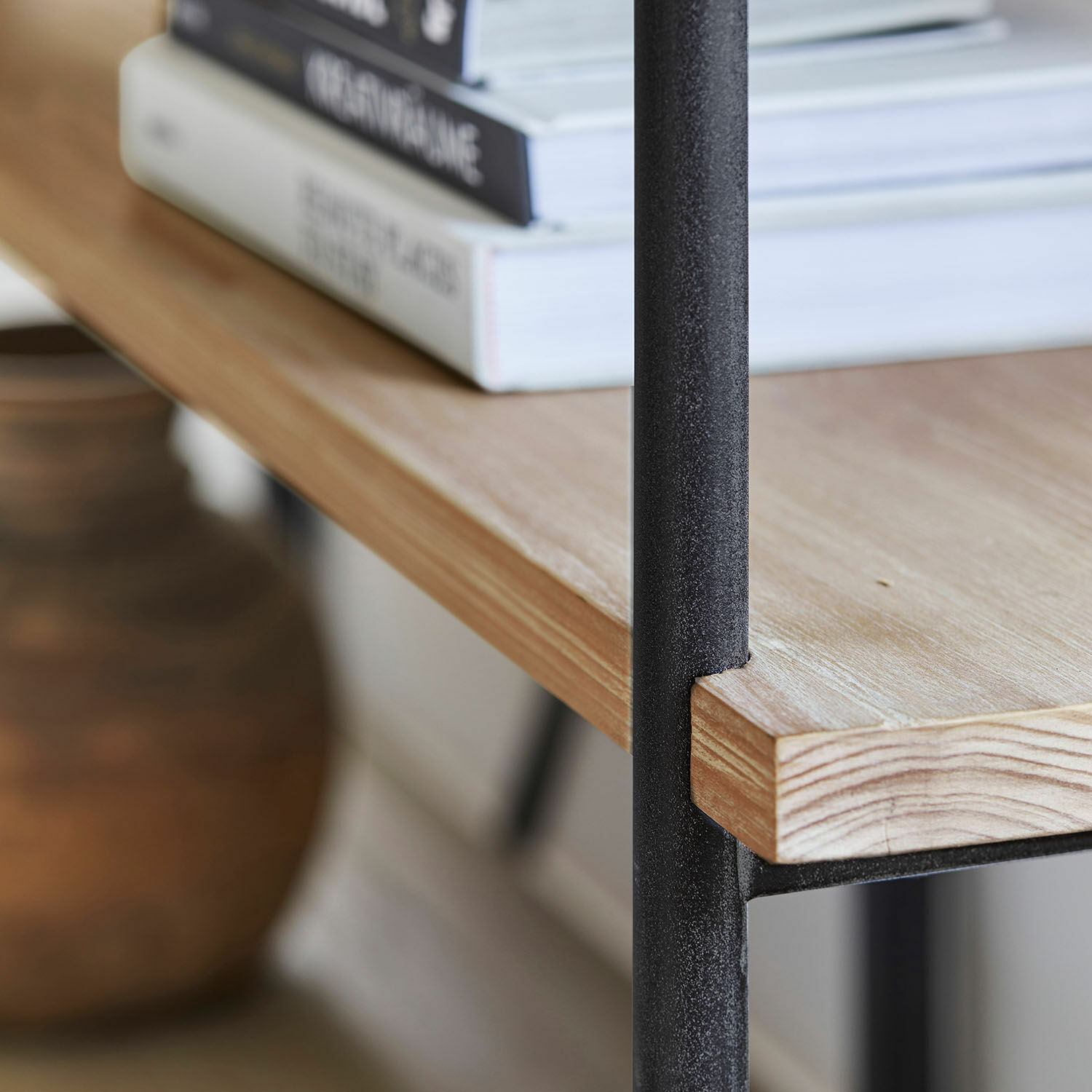 Heller Holz-Tischplatte mit schwarzem Metallgestell und Büchern darauf in modernem Raum