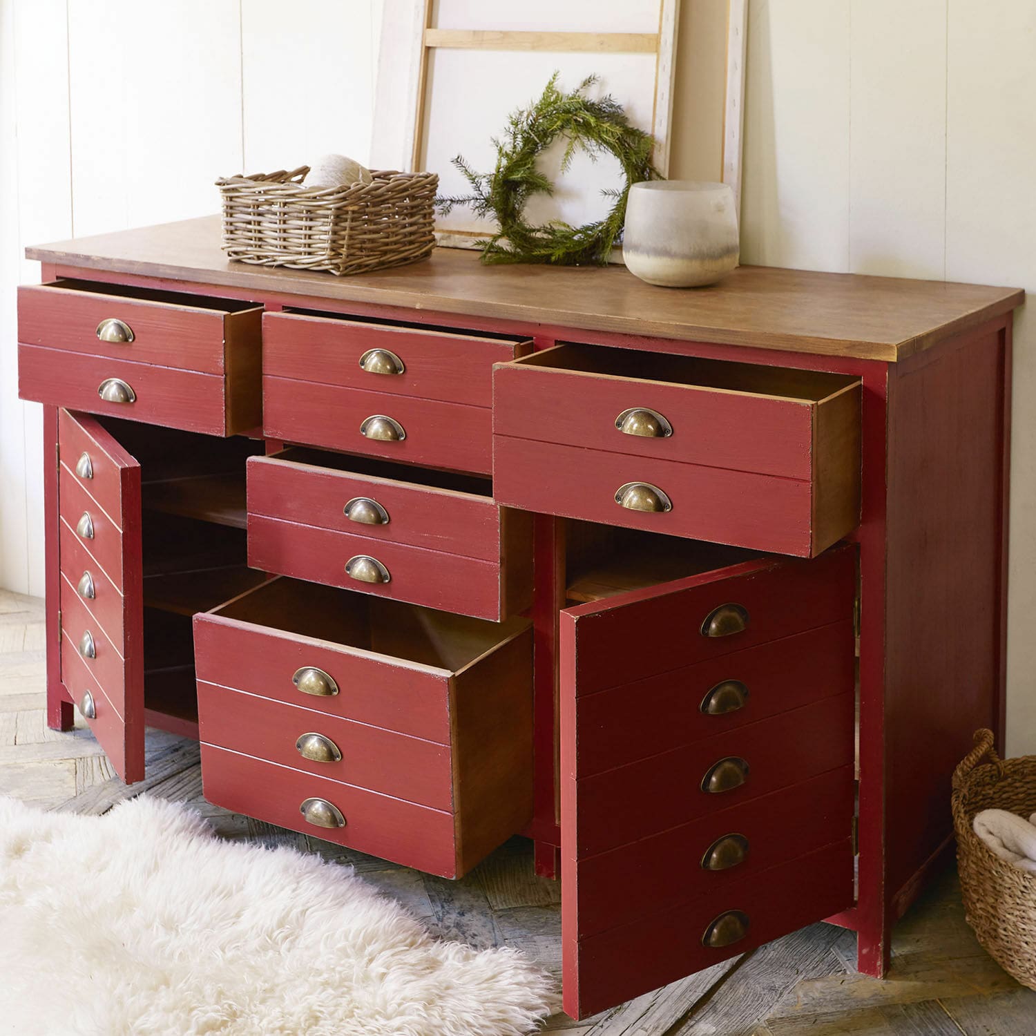 Roter Holzschrank mit vielen offenen Schubladen und vintage Metallgriffen in gemütlichem Raum