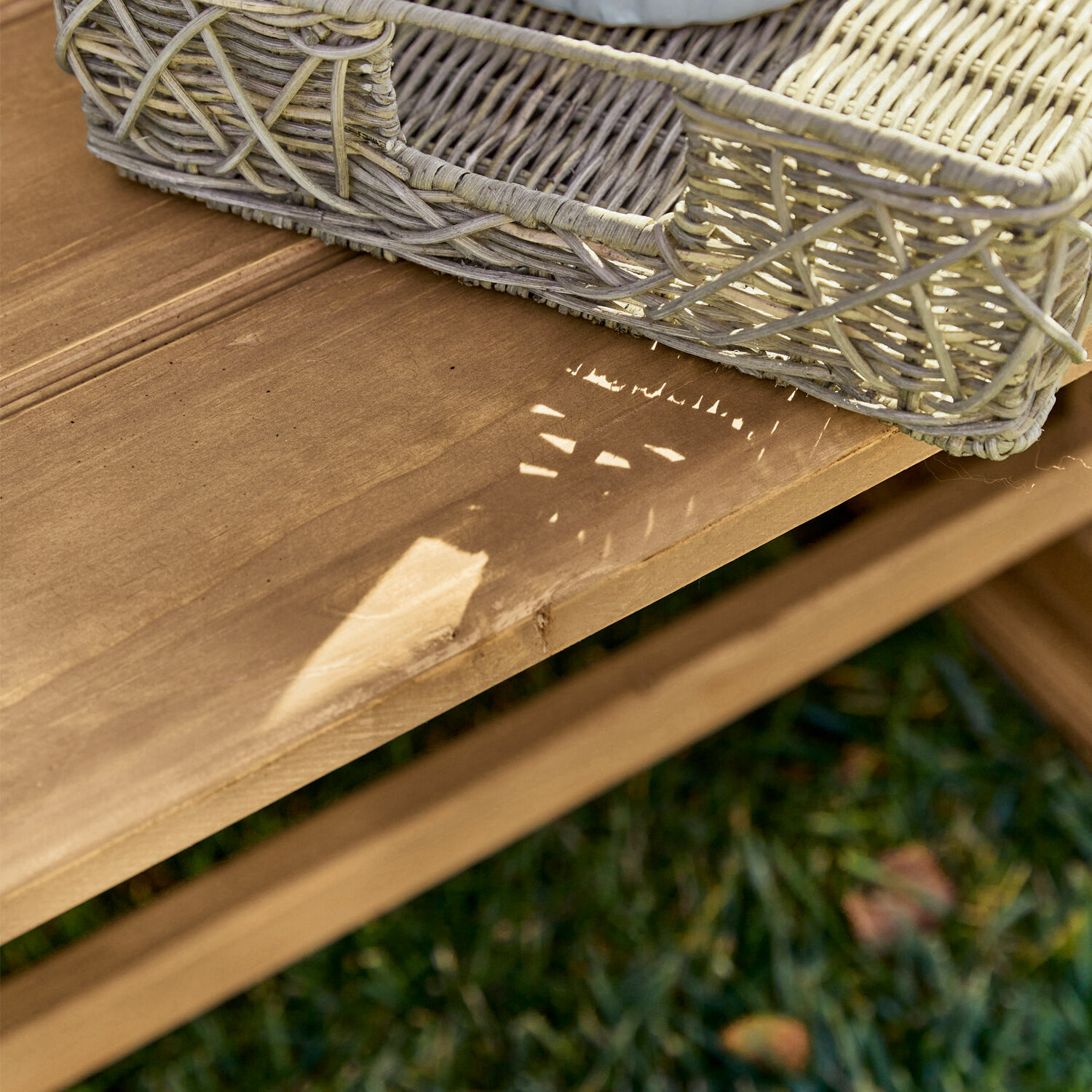 Natürlicher Korb aus Weide auf hellem Holztisch im Garten, rustikales Design