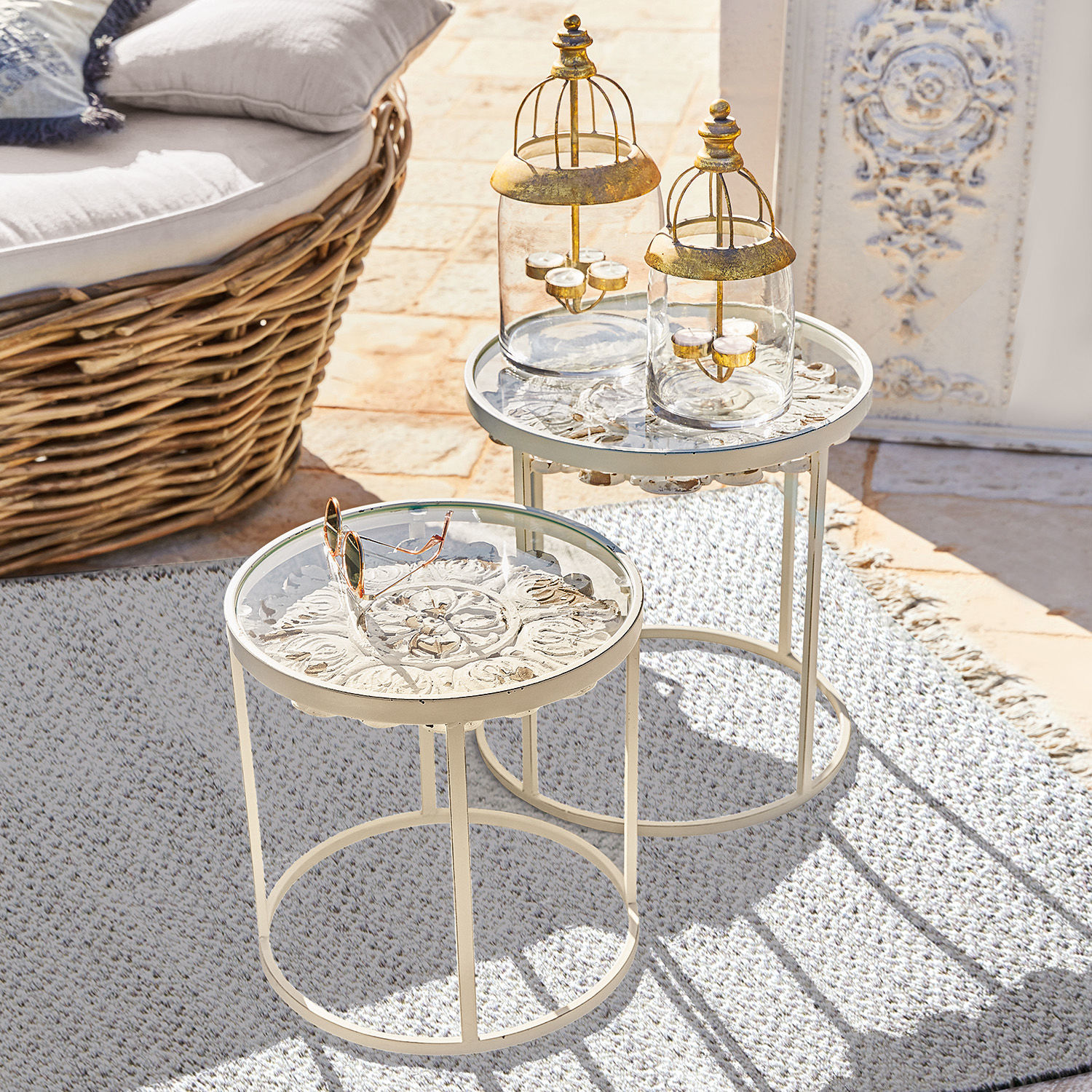 Zwei cremefarbene Metall-Beistelltische mit dekorativer Platte und Glaslaternen auf Terrasse
