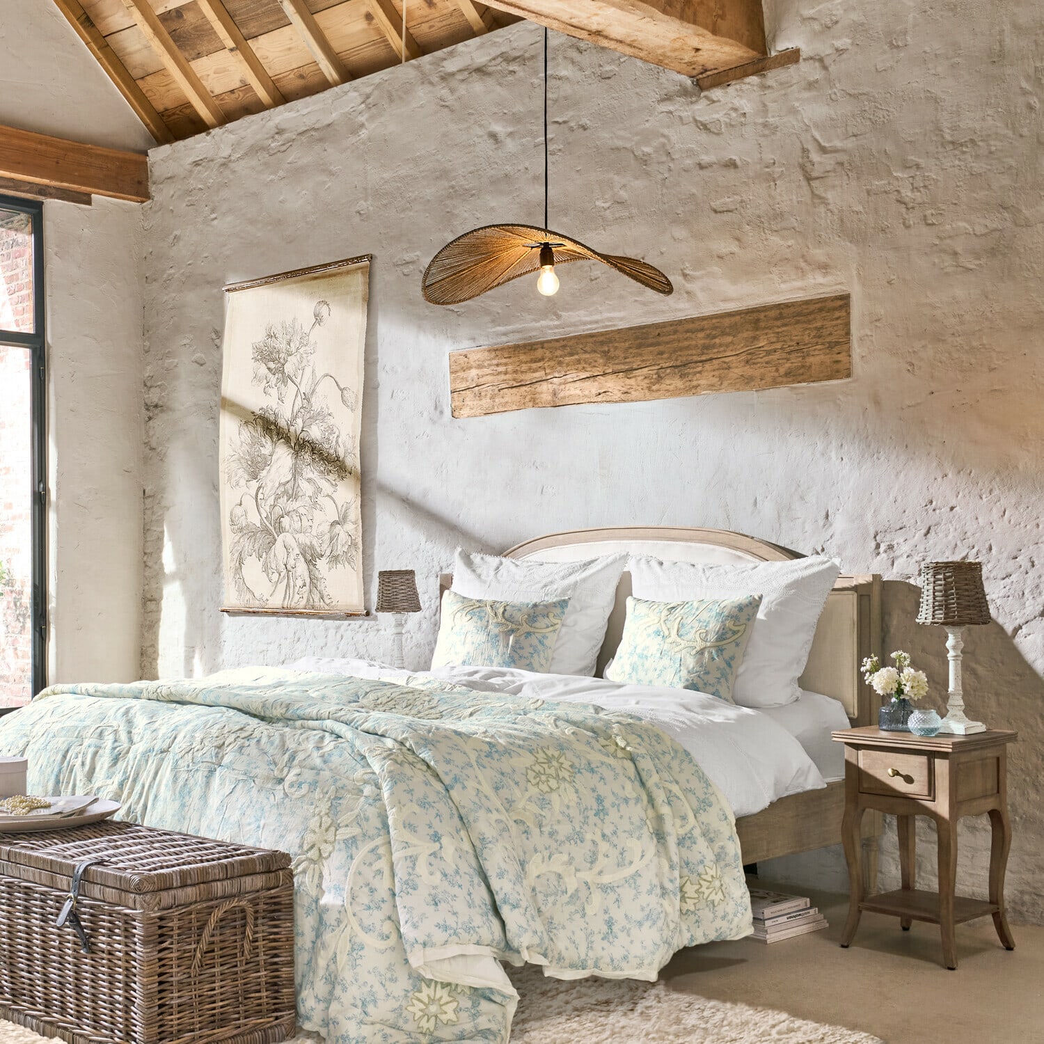 Gemütliches Schlafzimmer mit Holzbett und hellblauer, floral gemusterter Bettdecke aus Naturmaterialien