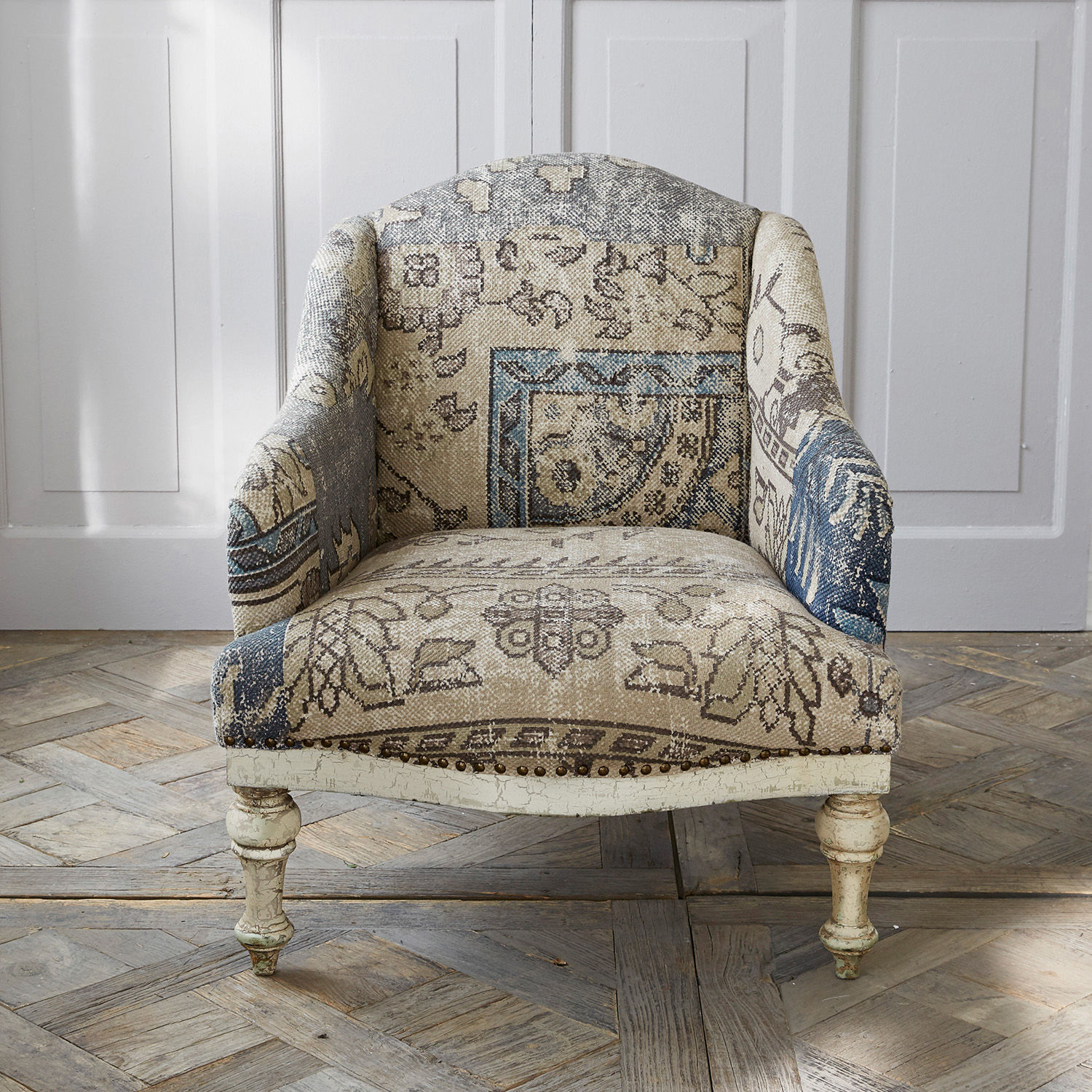 Vintage Sessel mit gemustertem beige-blauem Stoffbezug und antik wirkenden Holzbeinen