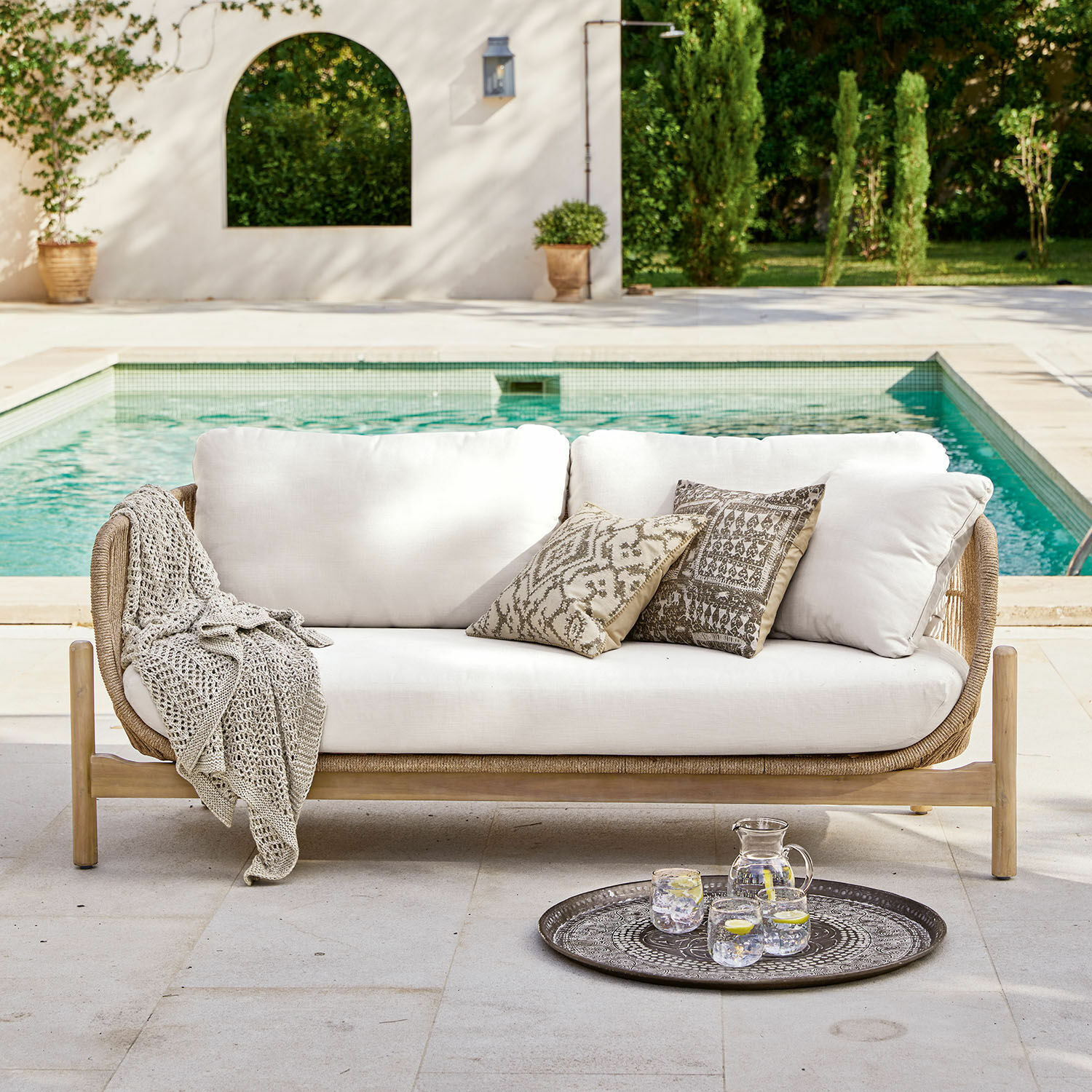 Sofa FSC®-100% Outdoor-Sofa mit hellen Kissen und Holzrahmen am Pool, dekorative Kissen und Decke
