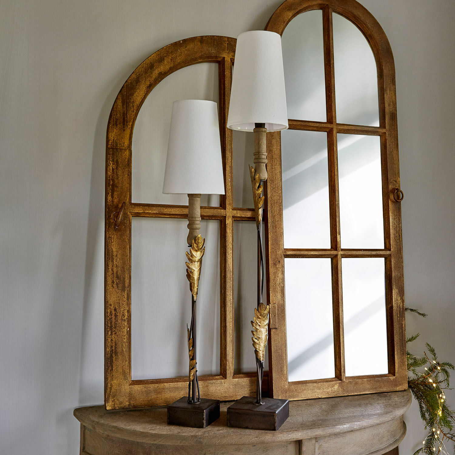 Zwei dekorative Tischlampen mit goldenen Metallblättern und weißen Lampenschirmen auf Holztisch