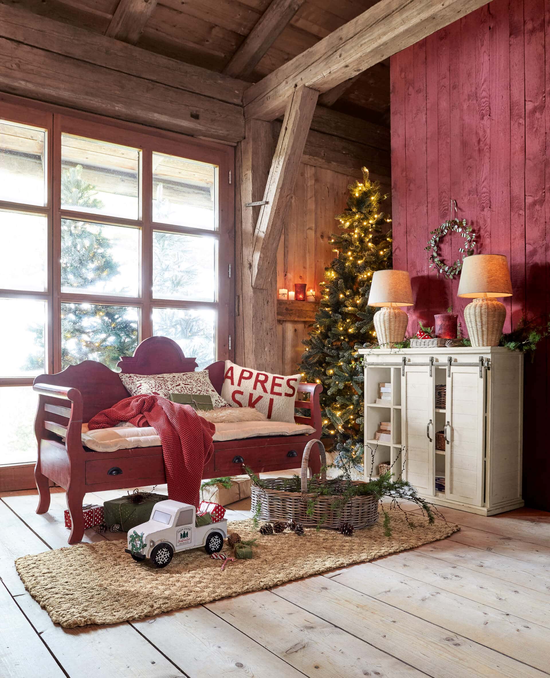 Gemütliches Wohnzimmer mit rotem Holzbett, beleuchtetem Weihnachtsbaum und Dekorationen auf Juteteppich