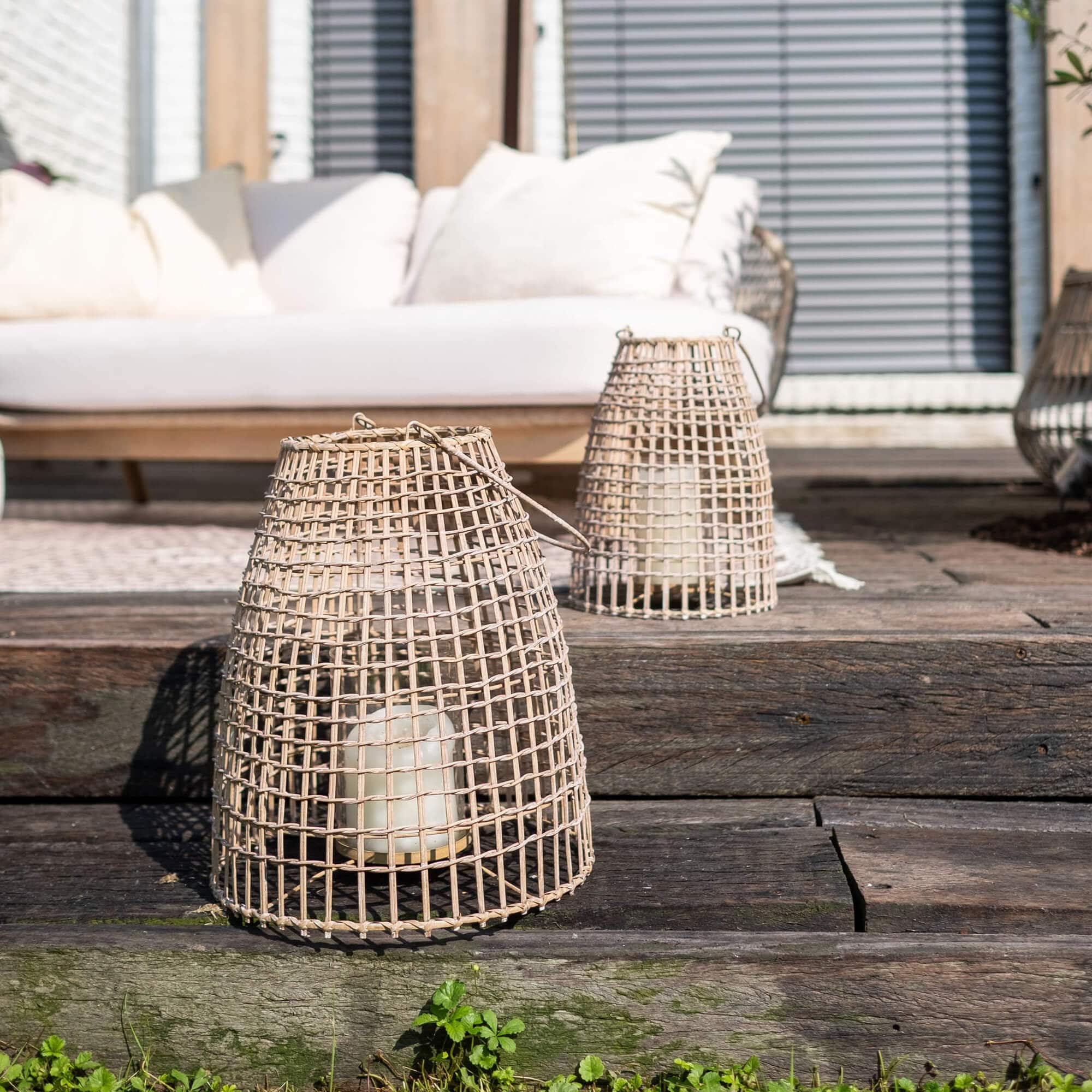 Laterne aus natürlichem Rattan mit weißer Kerze auf rustikalem Holzdeck
