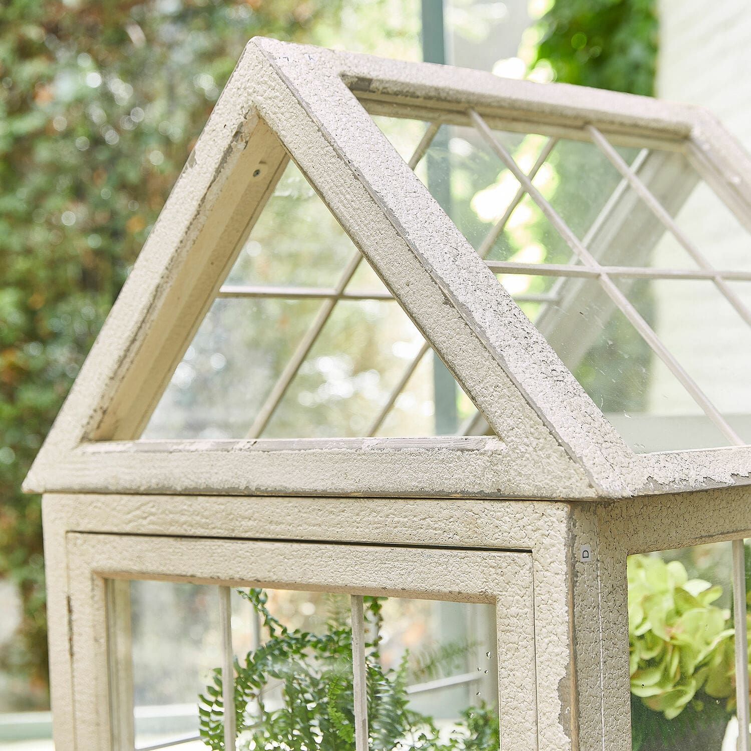 Kleine cremefarbene Metall-Gewächshaus mit Glasfenstern für Pflanzen im Haus und Garten