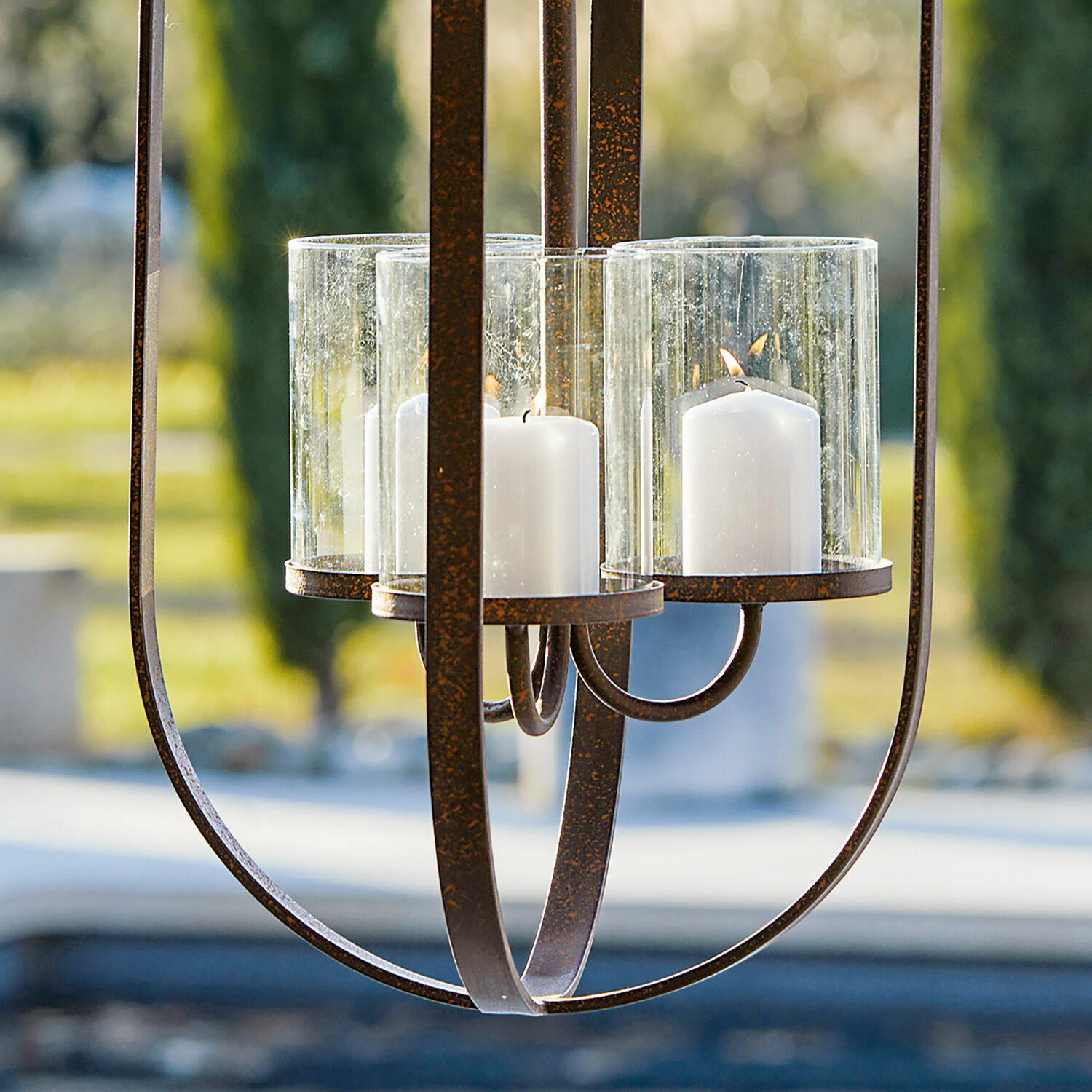 Hängender Metall-Kerzenhalter mit drei weißen Kerzen in Glasschirmen für Gartendekoration