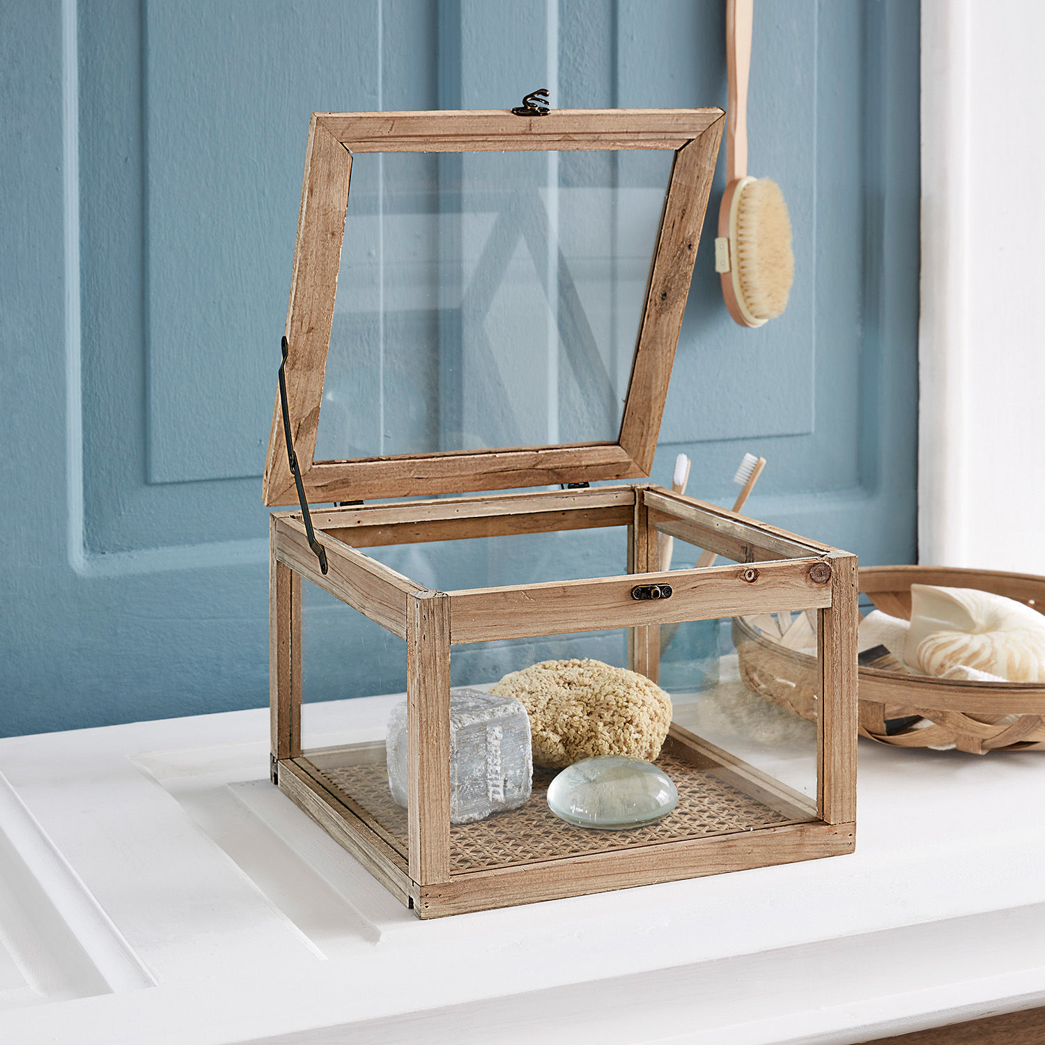 Holzbox mit transparenten Glasscheiben und aufklappbarem Deckel auf weißer Ablage im Bad