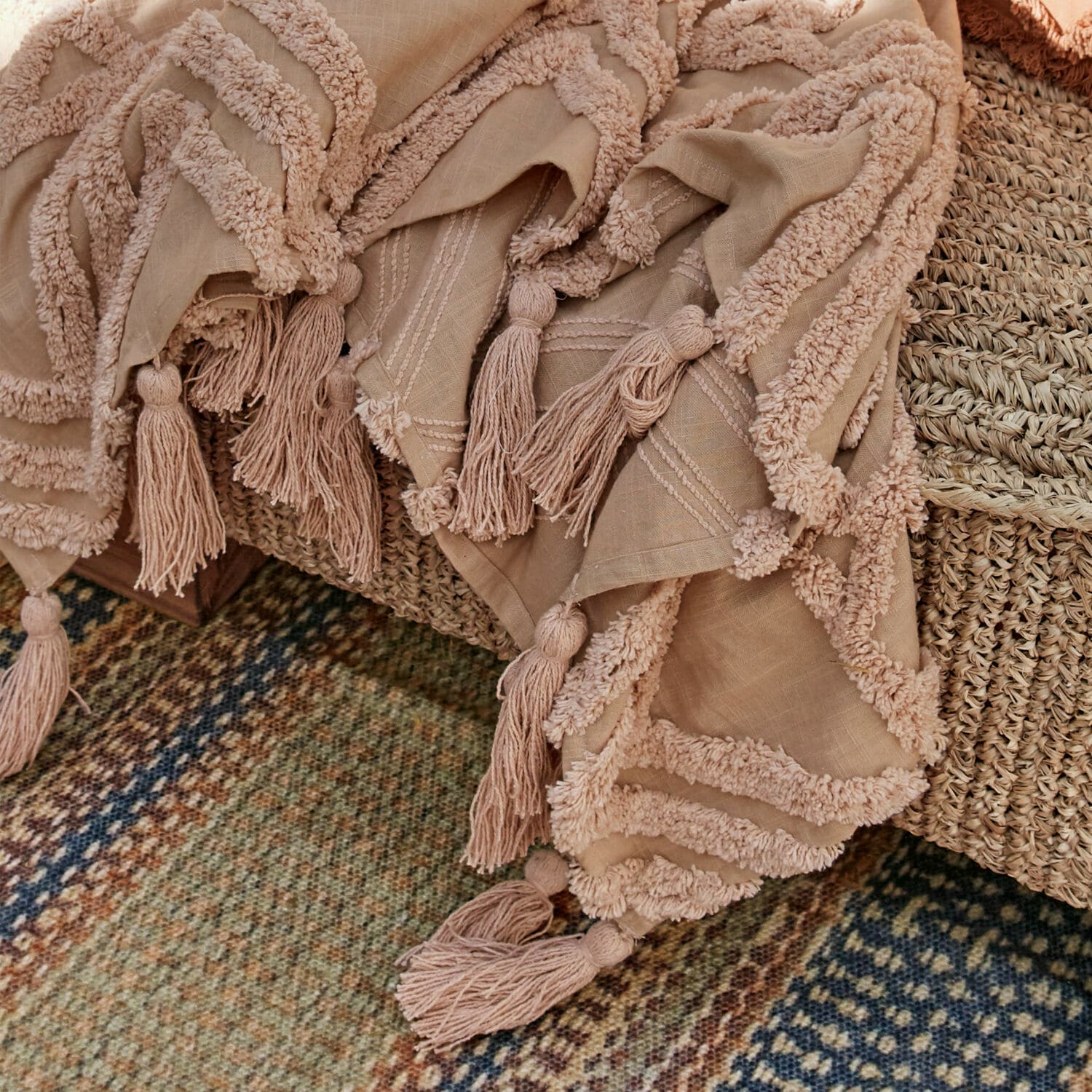 Beige Decke mit Quasten und weichen Verzierungen auf geflochtenem Möbelstück, Wohnkomfort