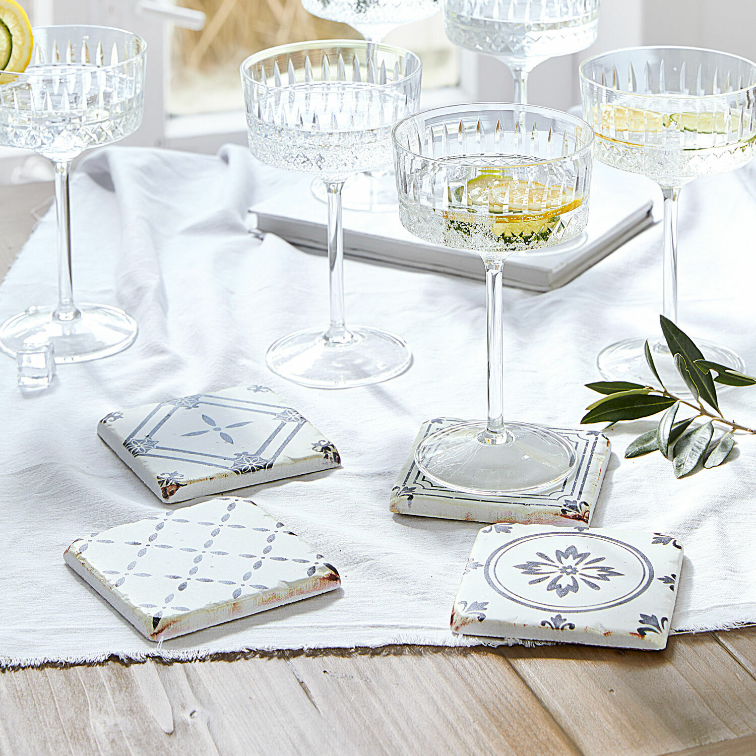 Untersetzer 4er Set Emma Set aus weißen und grauen Keramik-Untersetzern mit Muster auf hellem Holztisch mit Gläsern