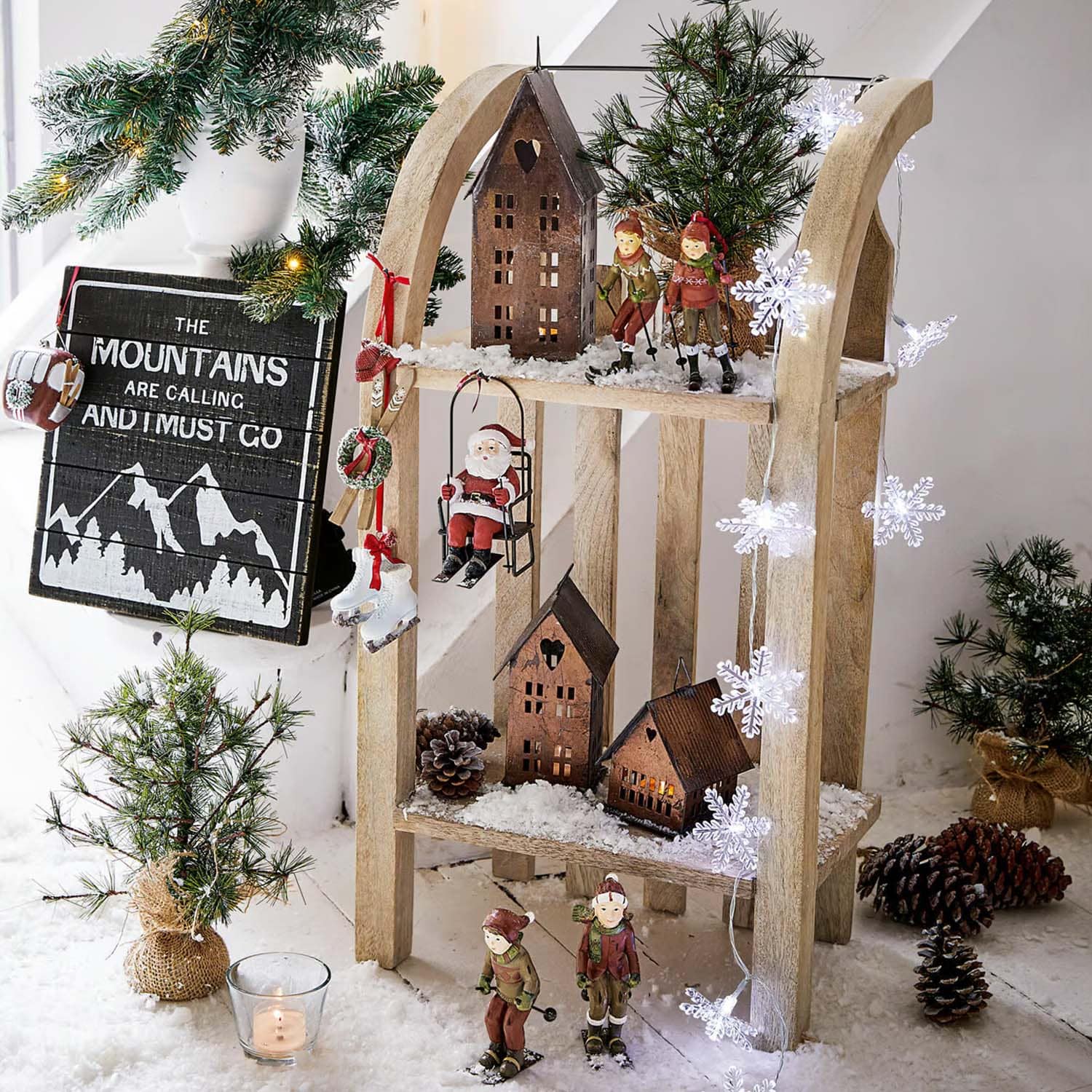 Weihnachtliche Holzdekoration mit Skifahrerfiguren, Weihnachtsmann und Häusern auf Kunstschnee