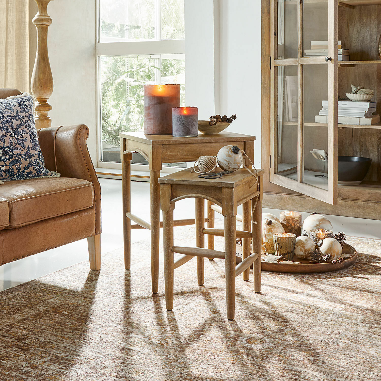 Holz-Beistelltische in Naturfarbe mit dekorativen Kerzen und Accessoires im Wohnzimmer