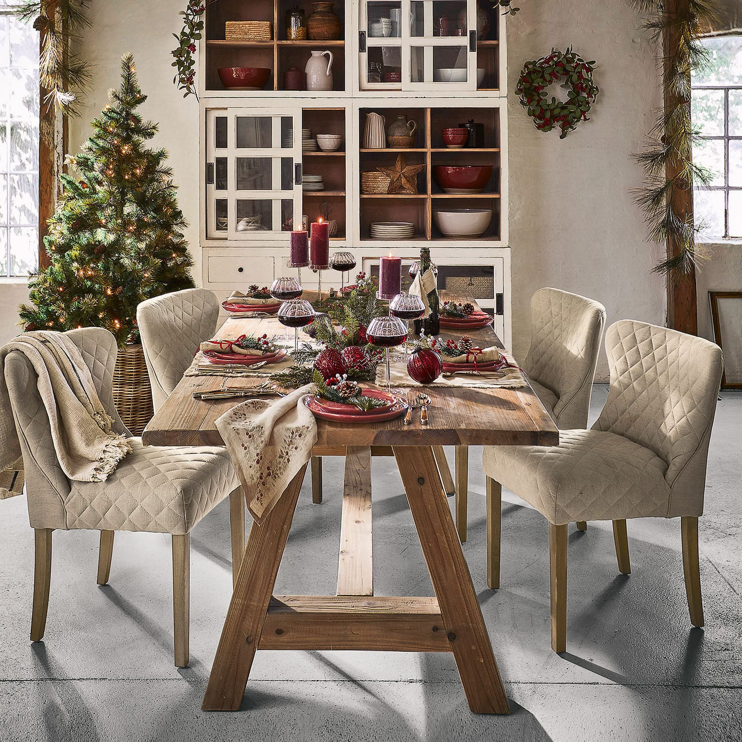 Rustikaler Holztisch mit beigen gepolsterten Stühlen und festlicher Weihnachtsdekoration im Esszimmer