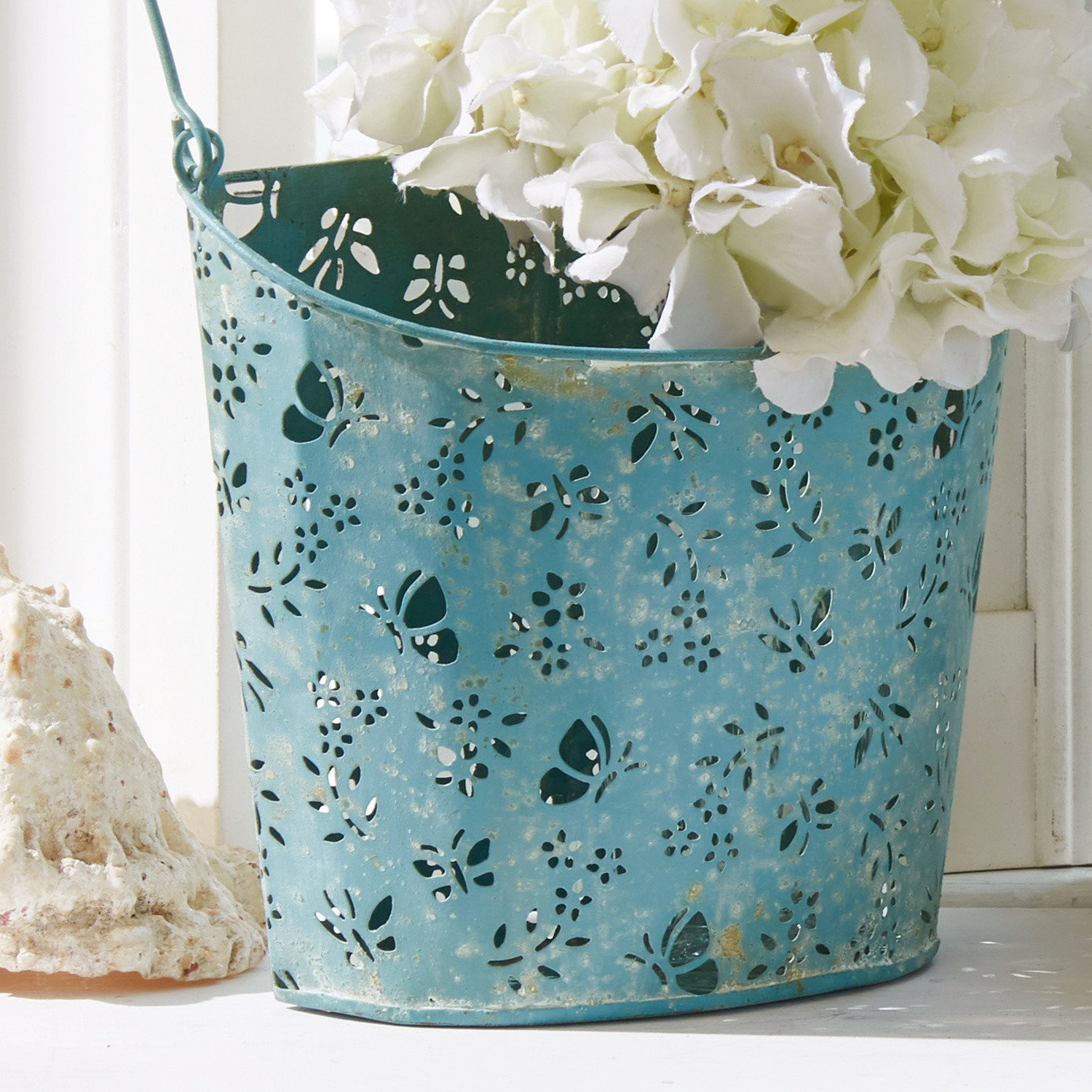 Blauer Metallübertopf mit filigranem Schmetterlings- und Blumenmuster für Wohnraumdeko