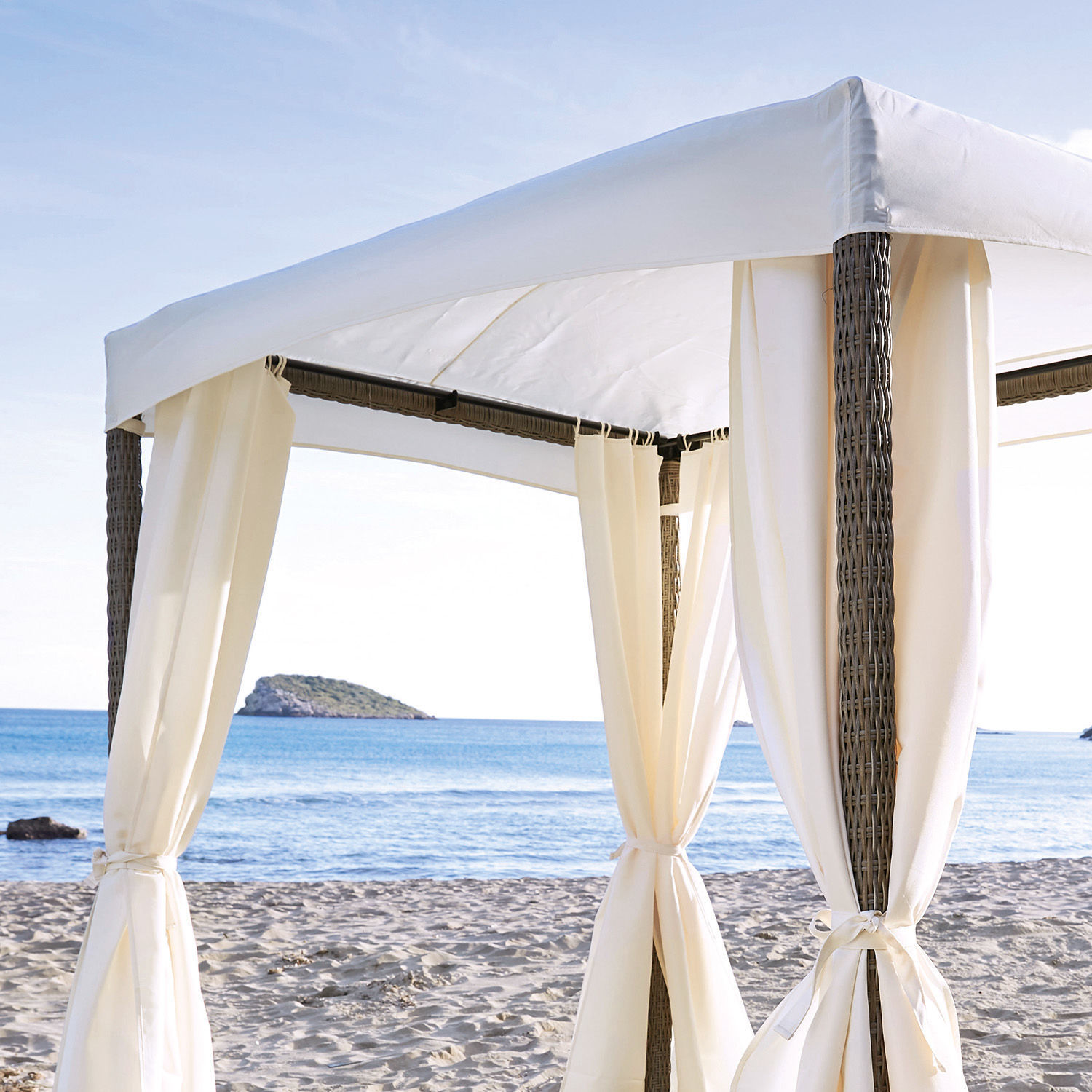 Weiße Pavillon aus Stoff und Rattan am Strand mit Meerblick, ideal zum Entspannen im Freien