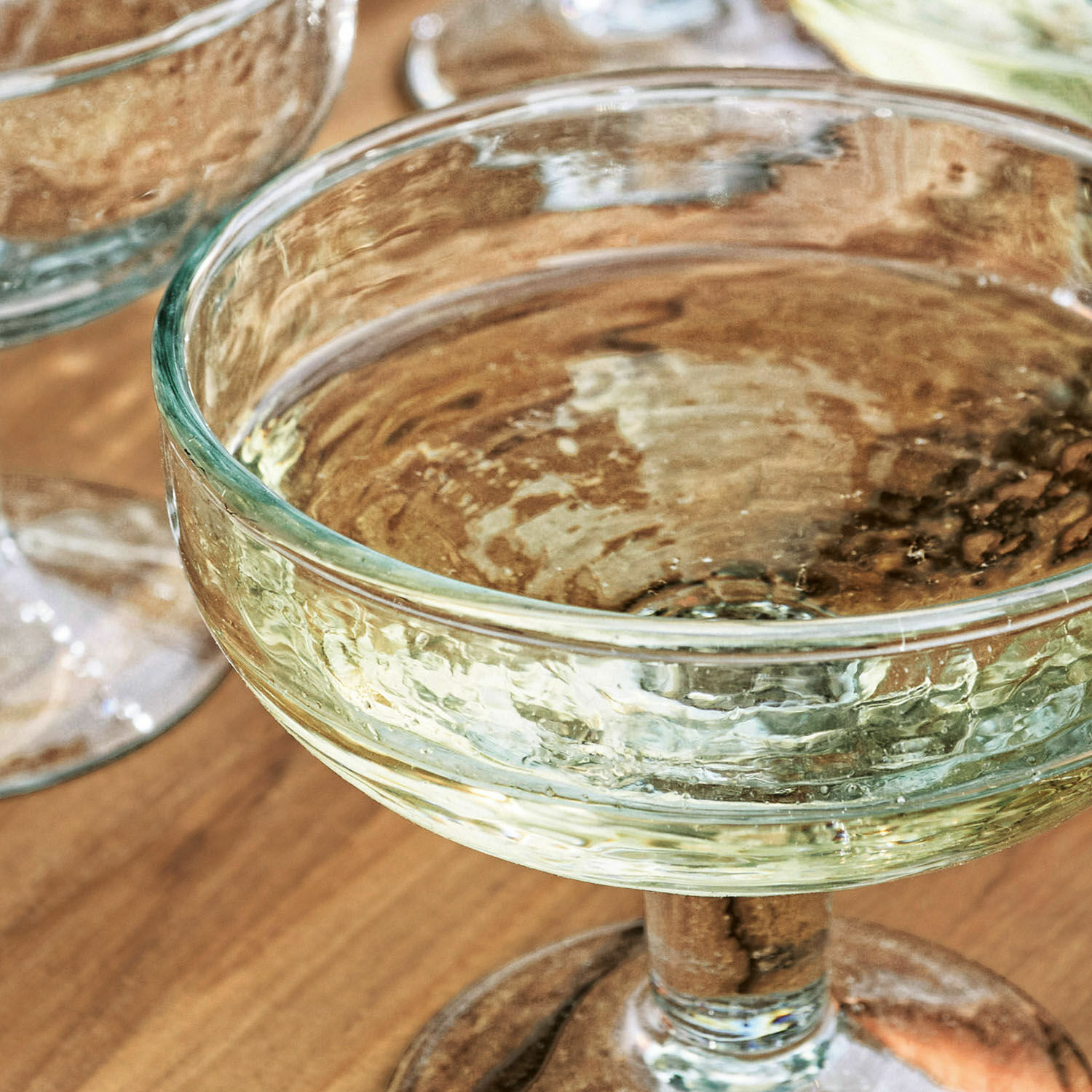 Transparantes Sektglas aus strukturiertem Glas auf Holztisch, elegantes Trinkglas
