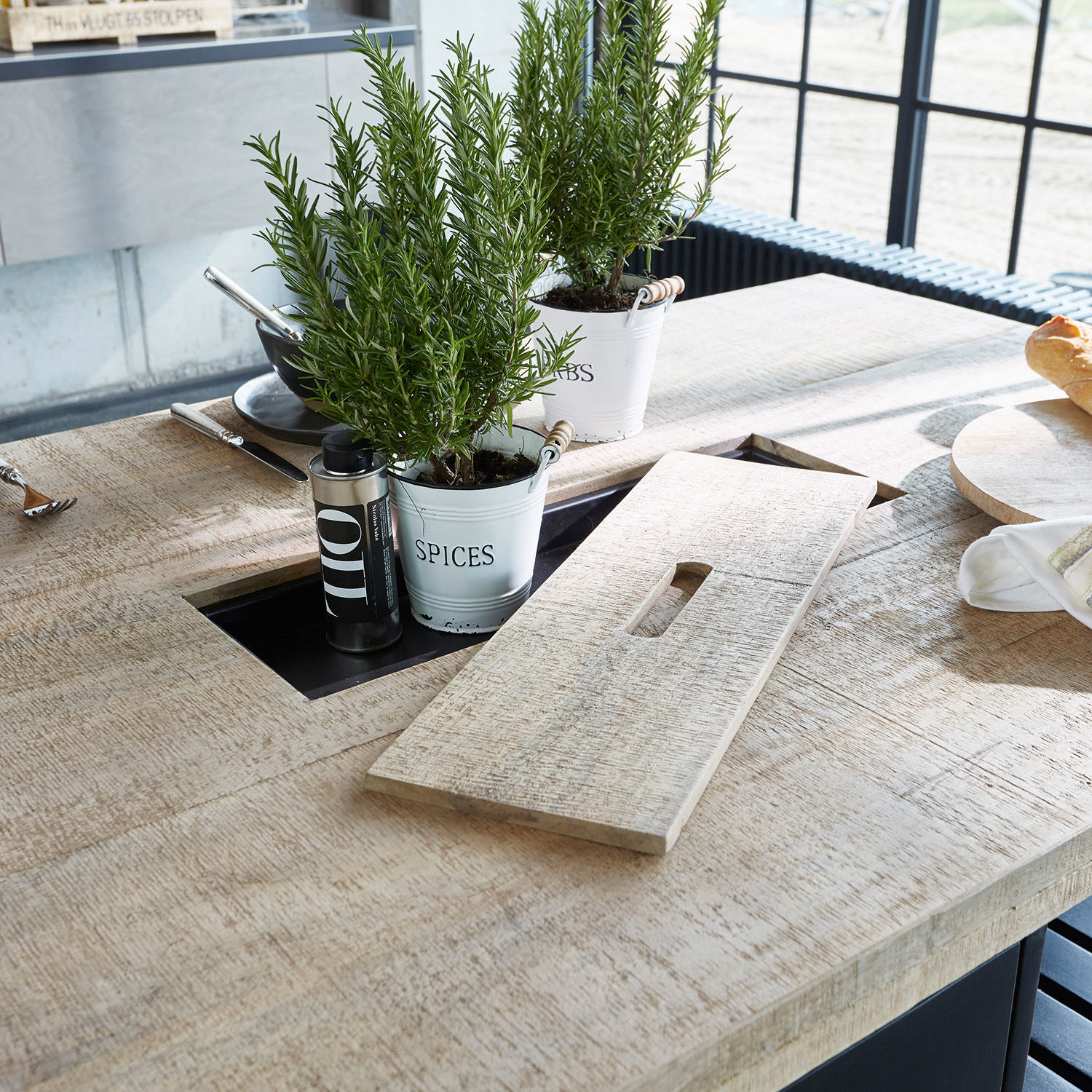 Heller Holztisch mit integriertem Fach für Gewürze und Kräuter in weißen Metalltöpfen