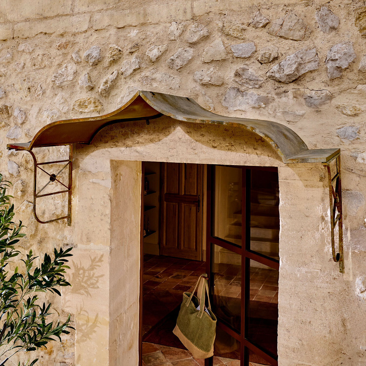 Rustikaler Metallvordach über Eingang mit Steinmauer, Schutz vor Regen