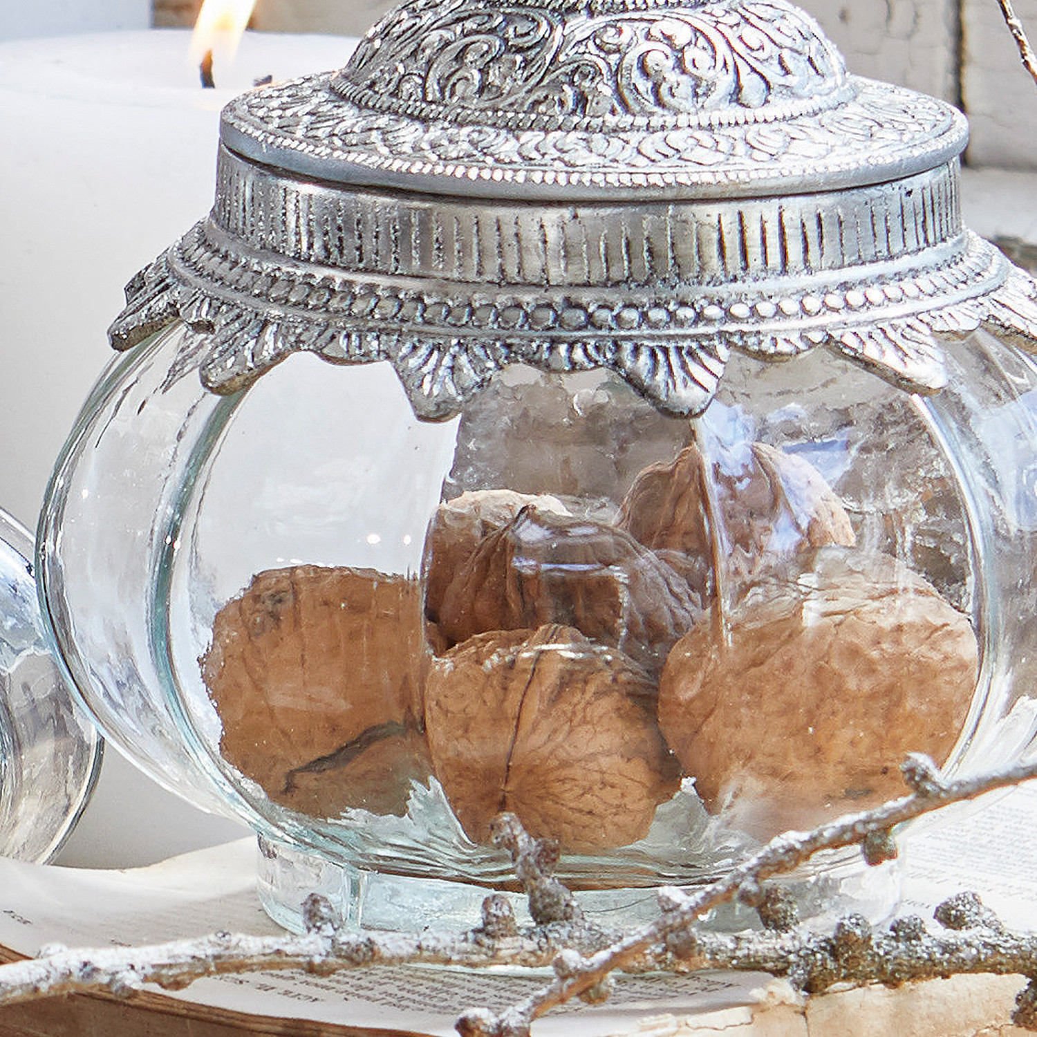 Glasbehälter mit silbernem Metalldeckel und Walnüssen als Tischdekoration