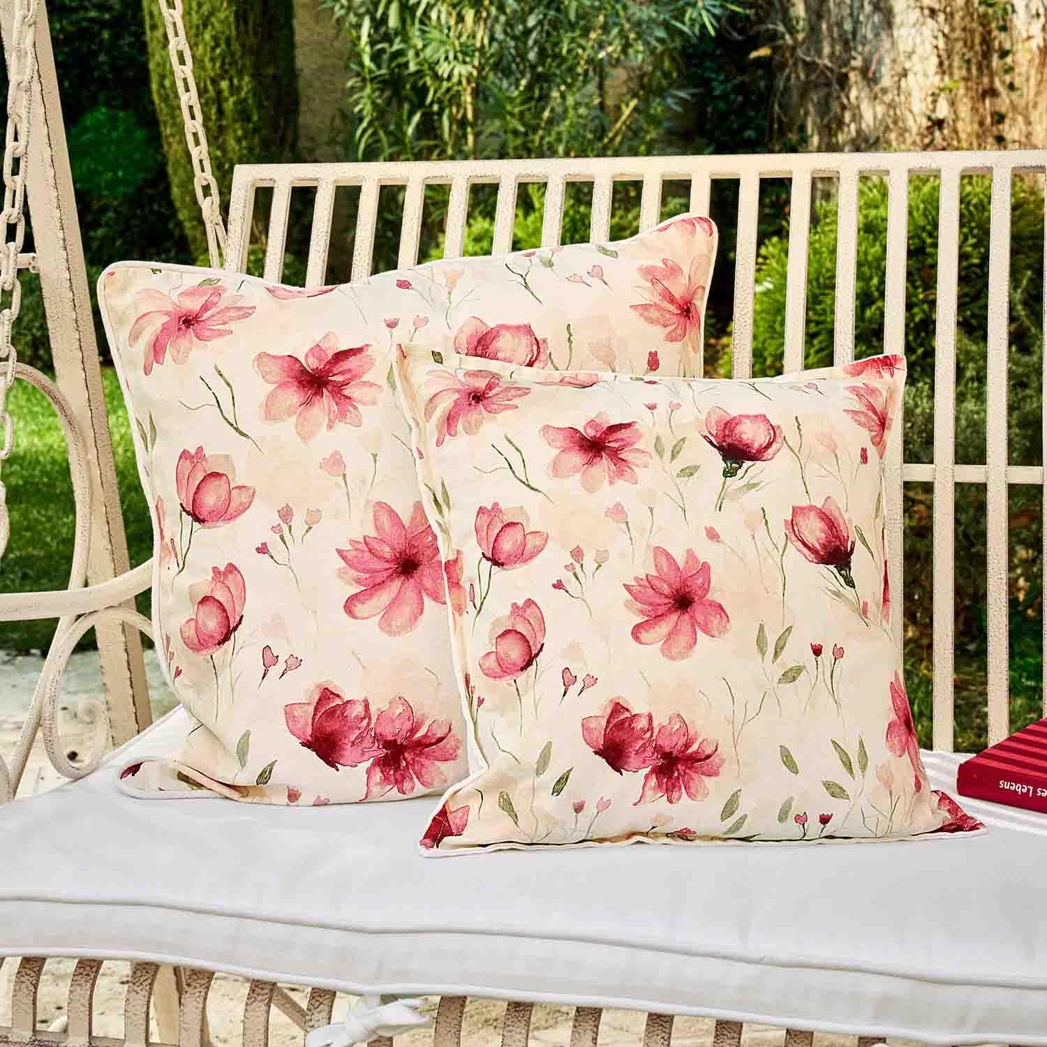Zwei dekorative Baumwollkissen in Creme mit rosa Blumenmuster auf einer Gartenschaukel aus Metall