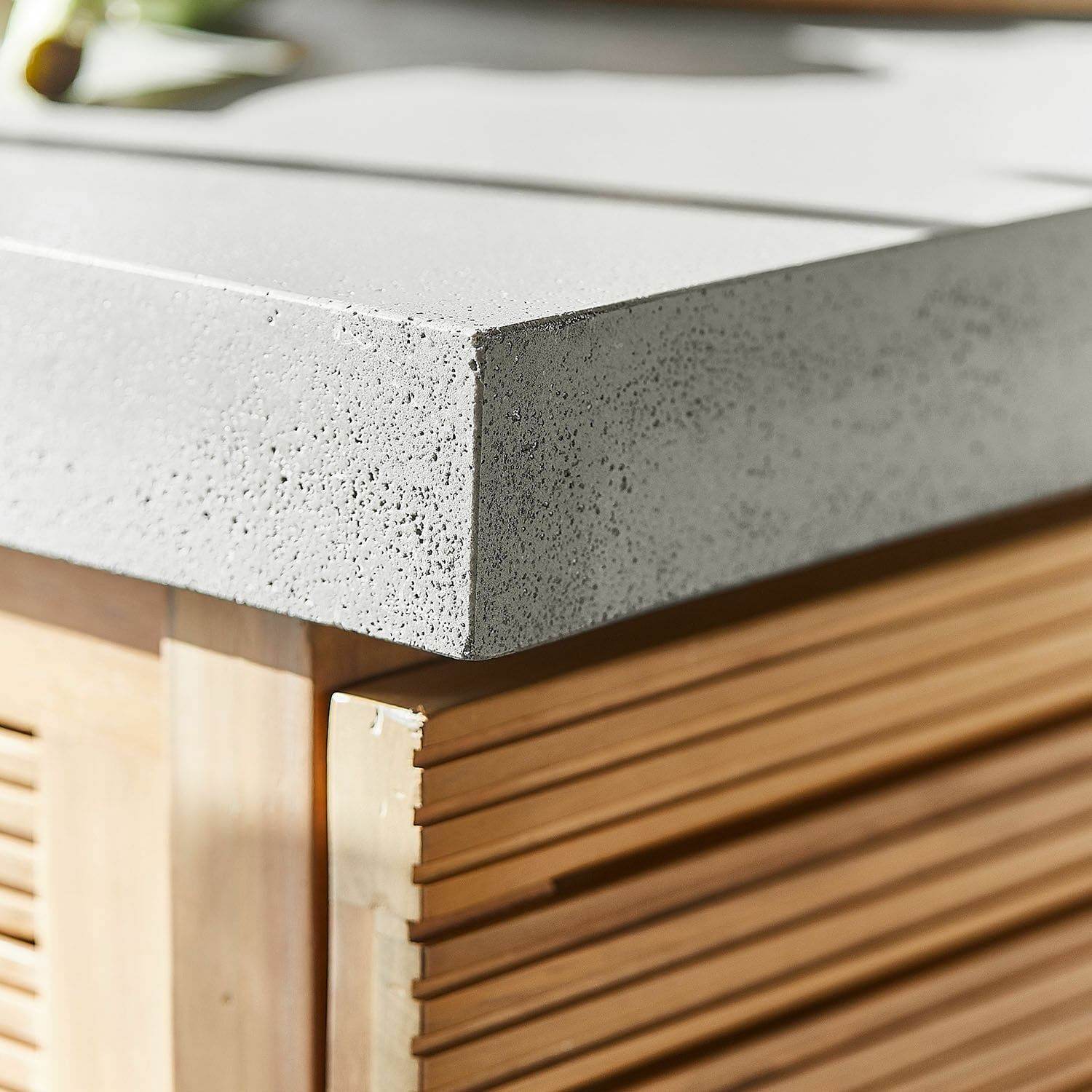 Küchenarbeitsplatte aus hellgrauem Beton auf Holzunterbau mit dekorativen Rillen
