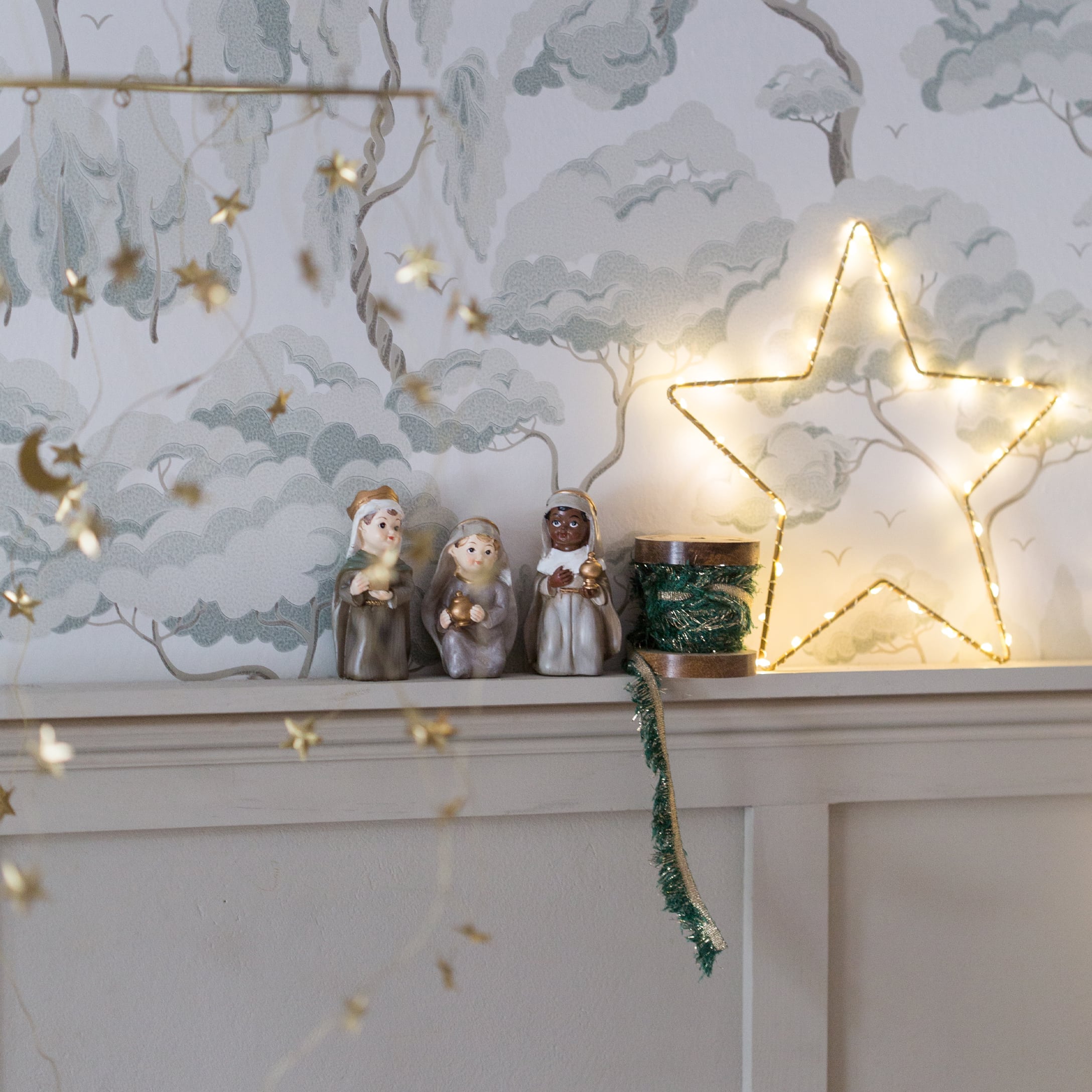 Weihnachtsdekoration mit drei Heiligen Drei Könige Figuren und beleuchteter Stern auf weißem Regal